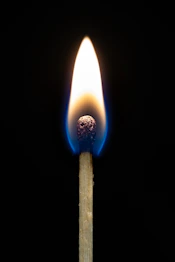 A lit match burning brightly against a dark background