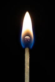 A lit match burning brightly against a dark background