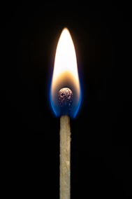 A lit match burning brightly against a dark background