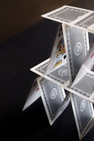 A house of cards balanced precariously on a dark surface.
