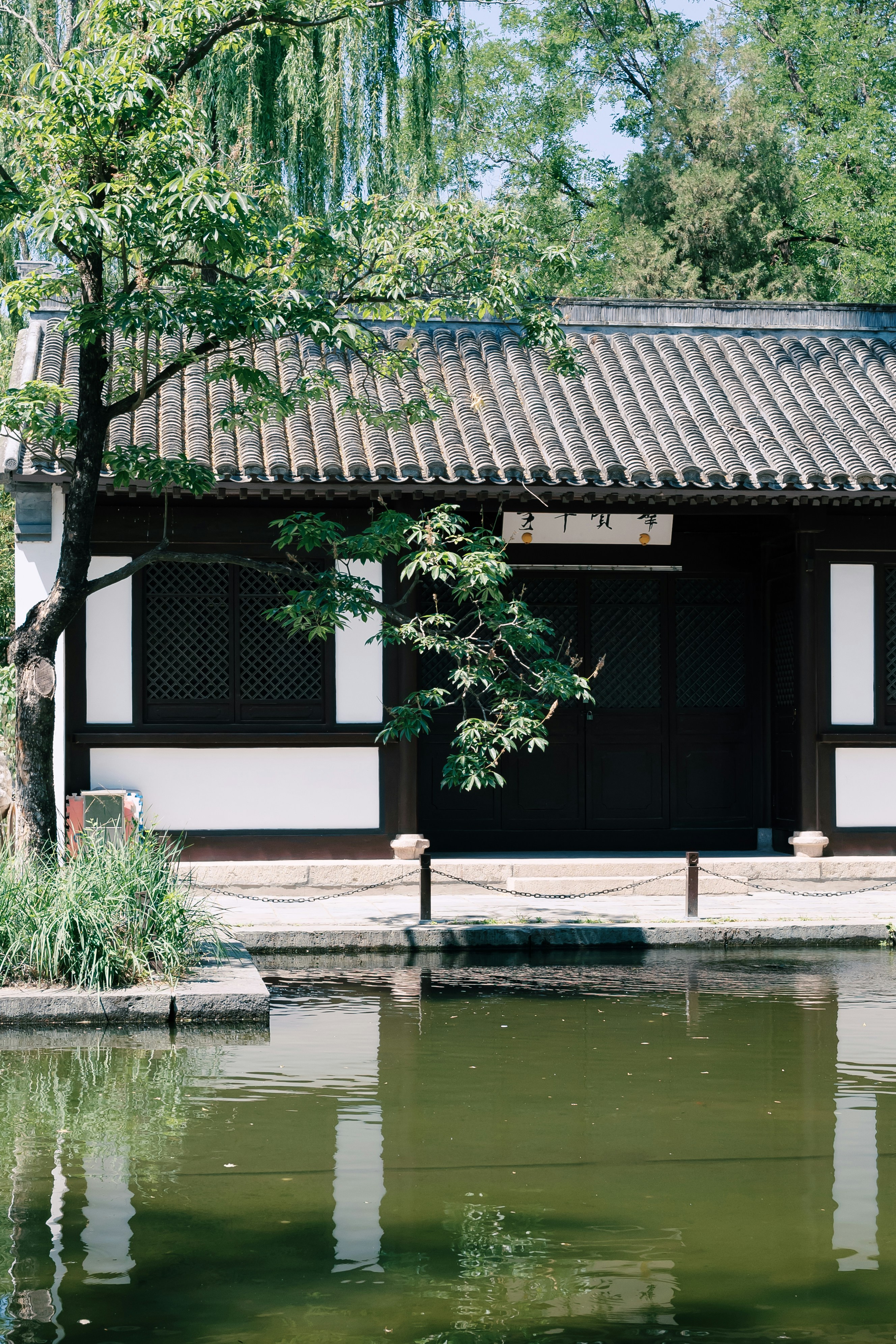 Traditional building beside a calm pond with trees