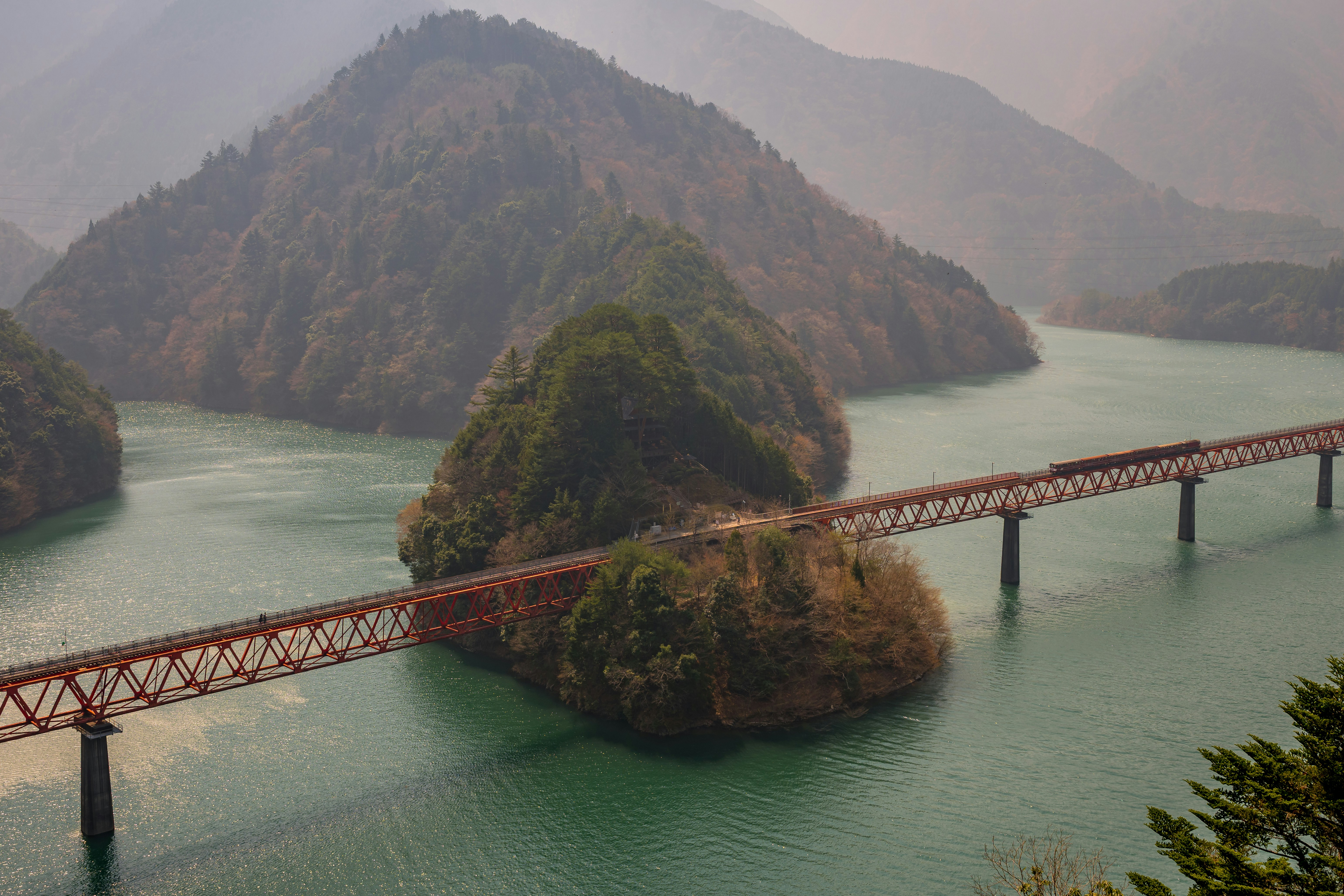ターコイズブルーの湖に架かる橋を渡る列車