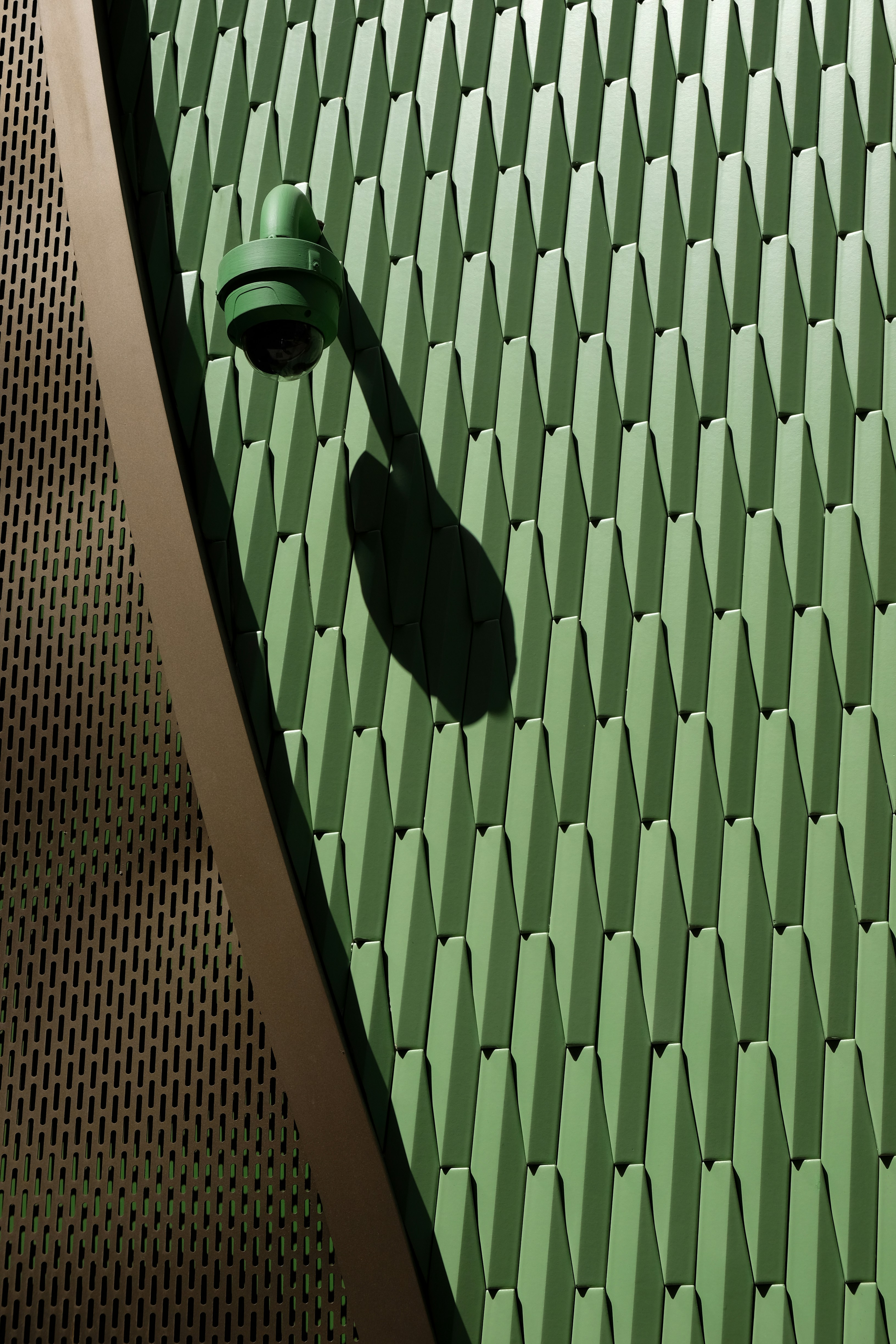 Green security camera mounted on textured wall