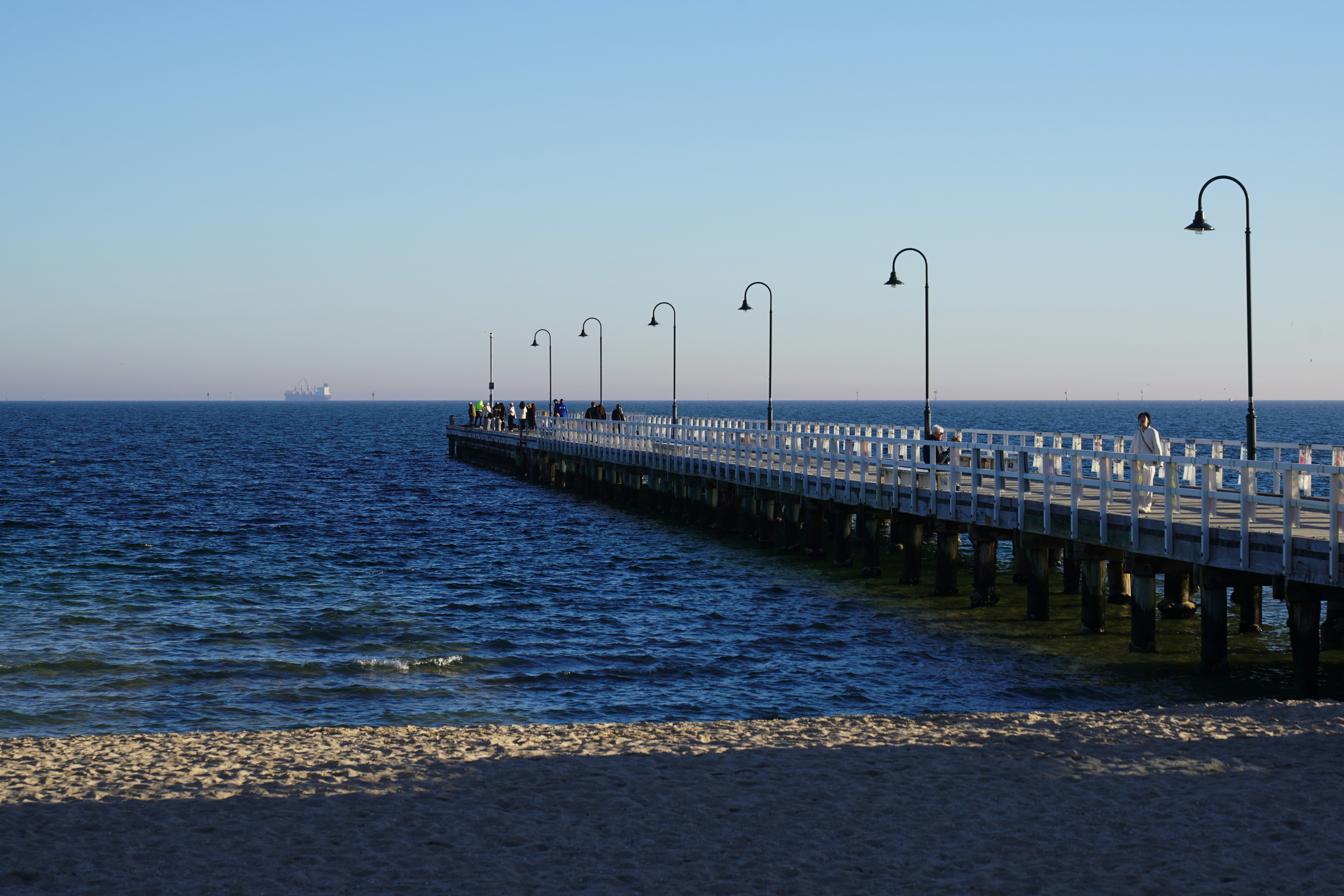 A long pier extends over the ocean at sunset
