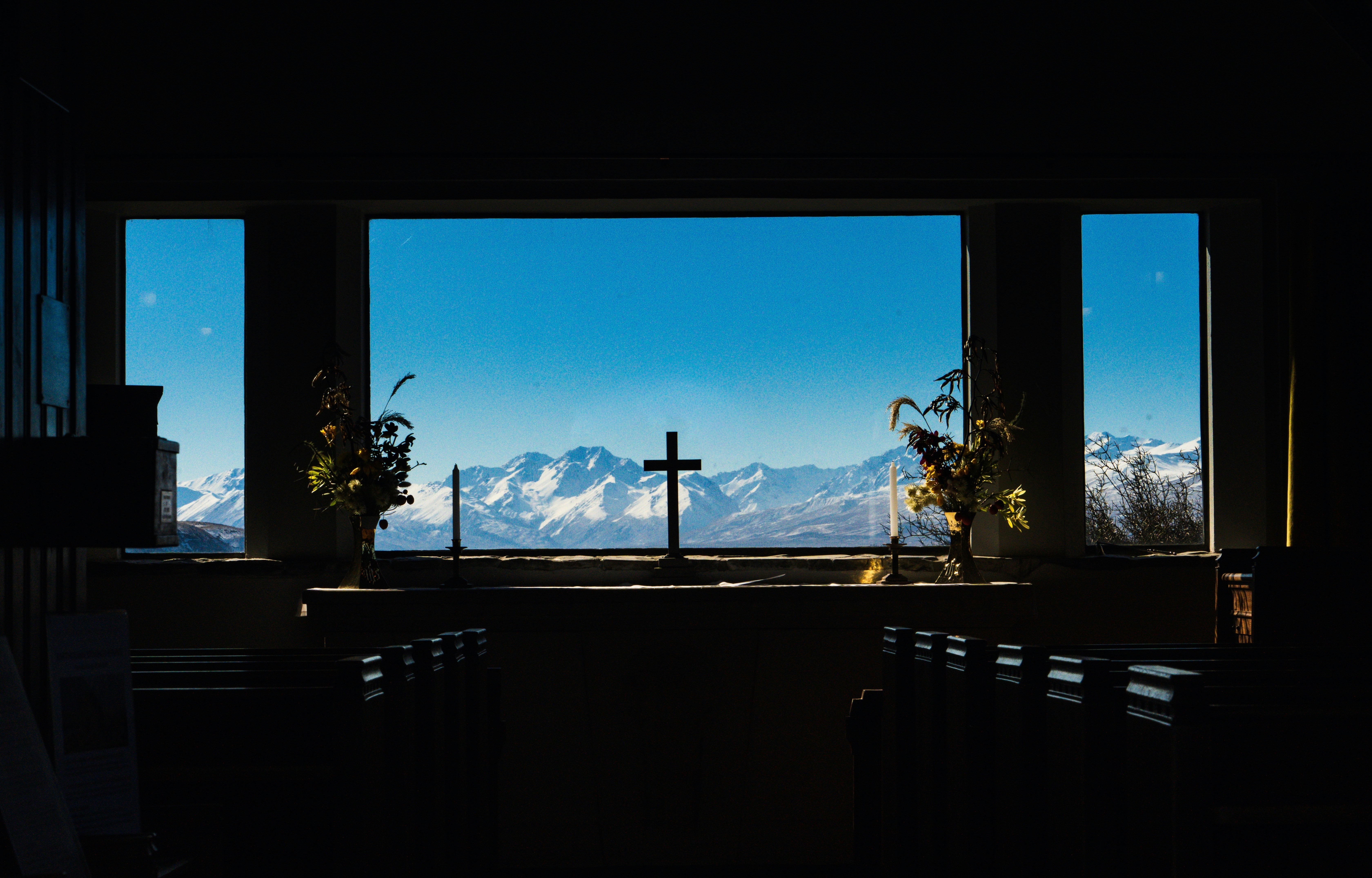 Cross and snow-capped mountains seen through window