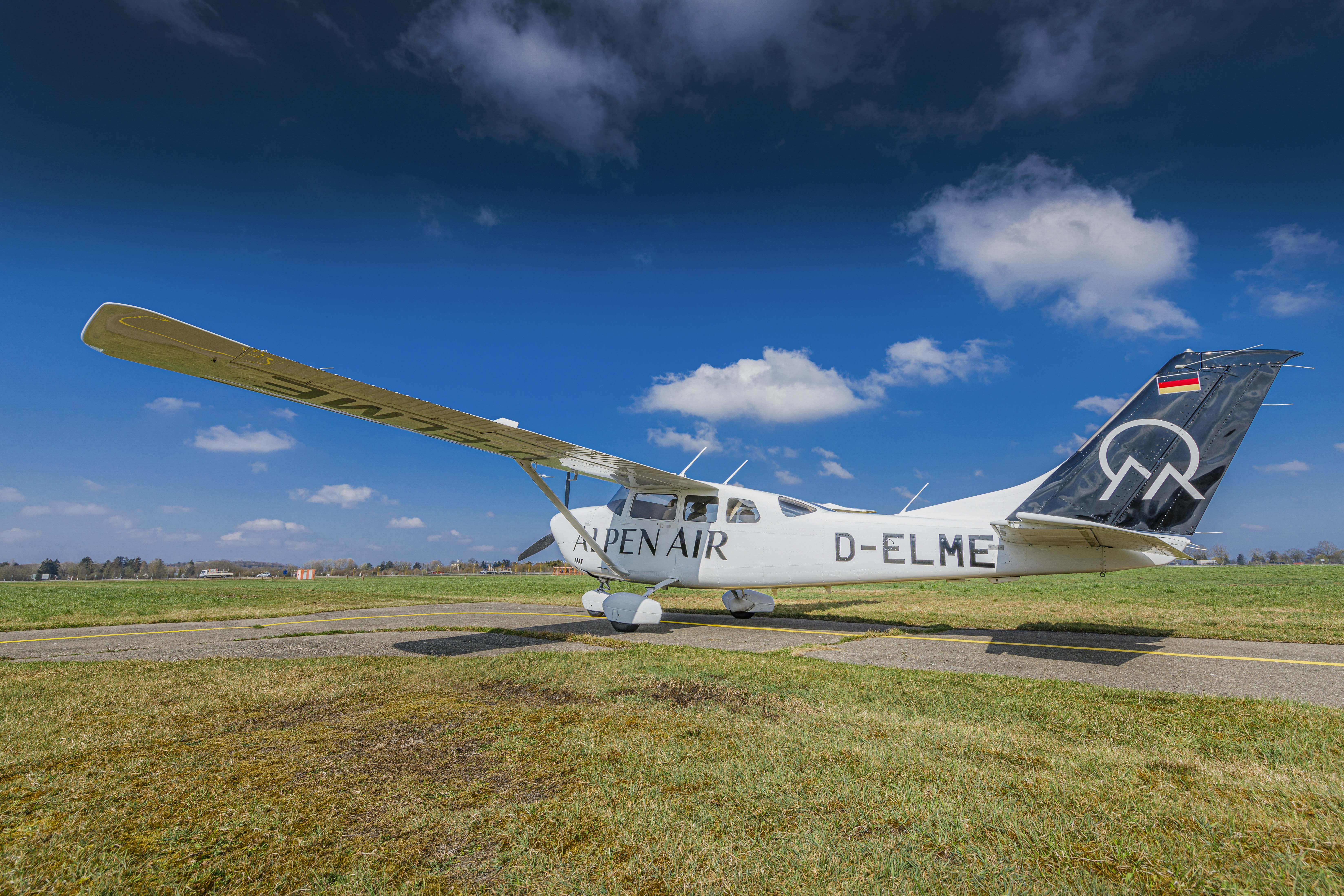 Small airplane parked on a runway under blue sky.