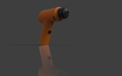 Orange cordless drill on a reflective surface.
