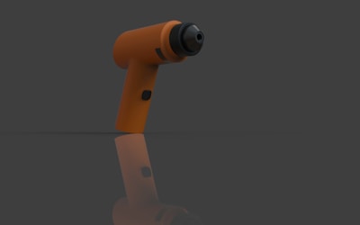 Orange cordless drill on a reflective surface.