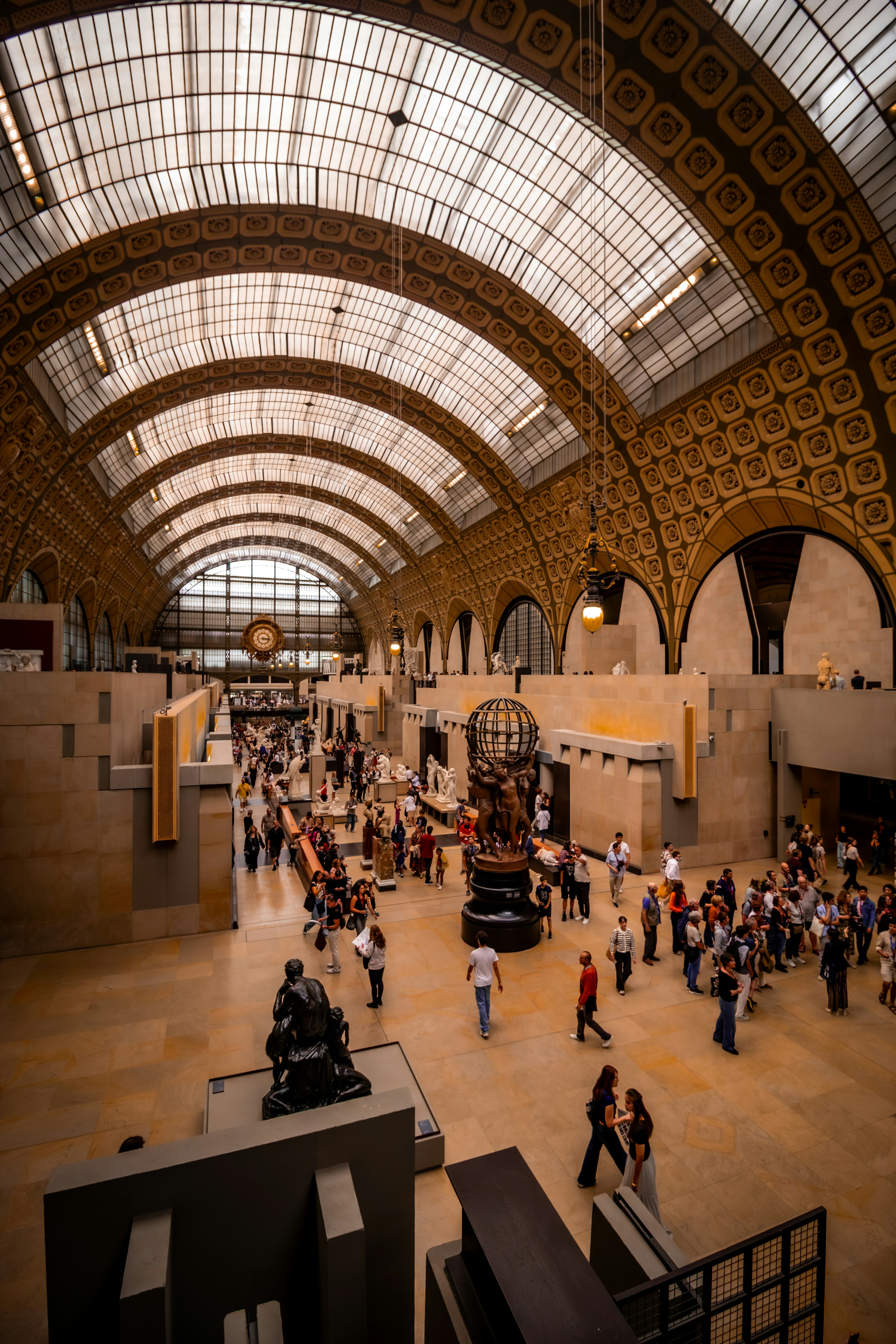 Gran nave interior del Musée d'Orsay, París, Francia, con visitantes bajo la vasta bóveda de cristal y hierro.