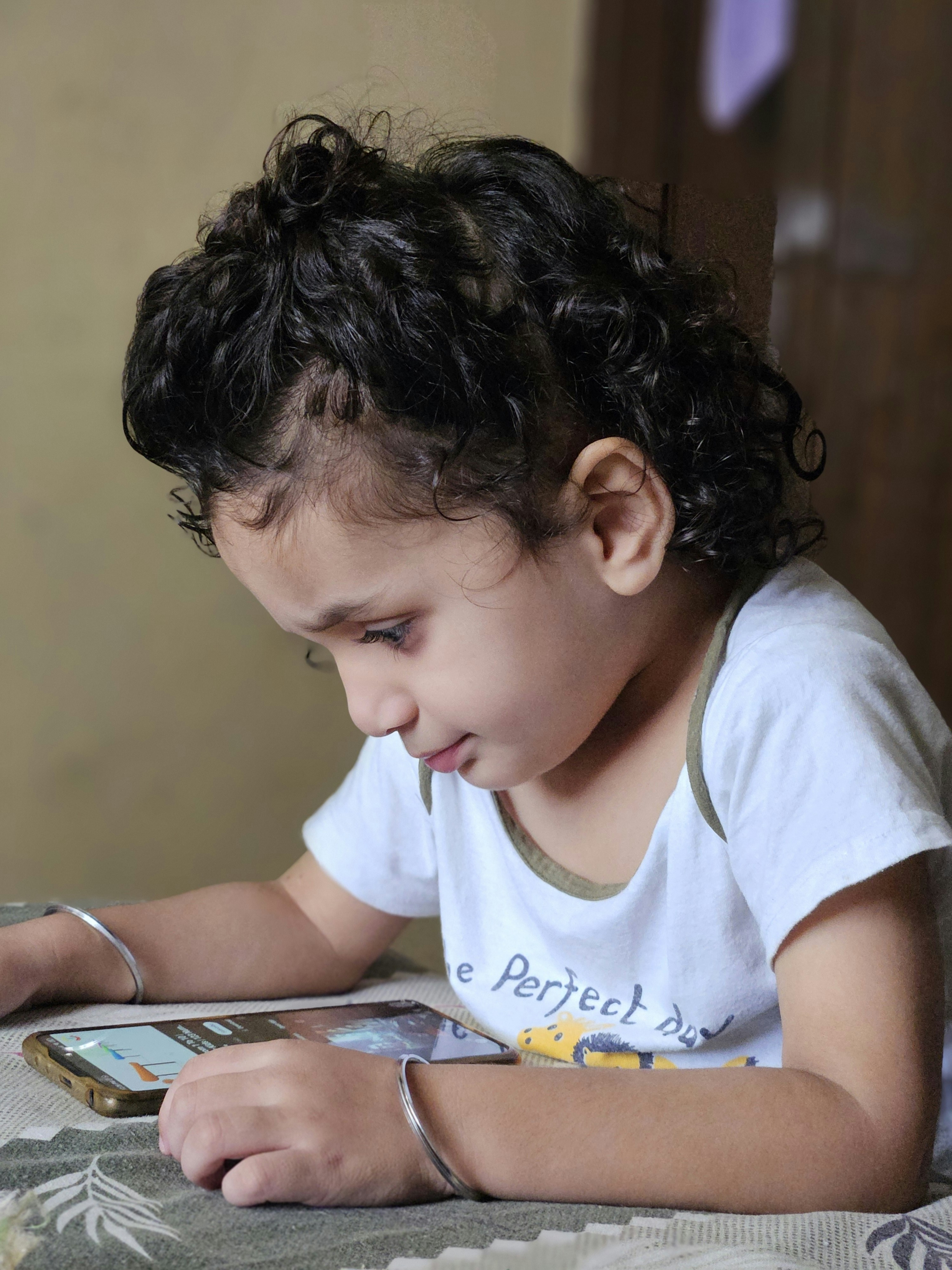 Young child focused on a smartphone screen.