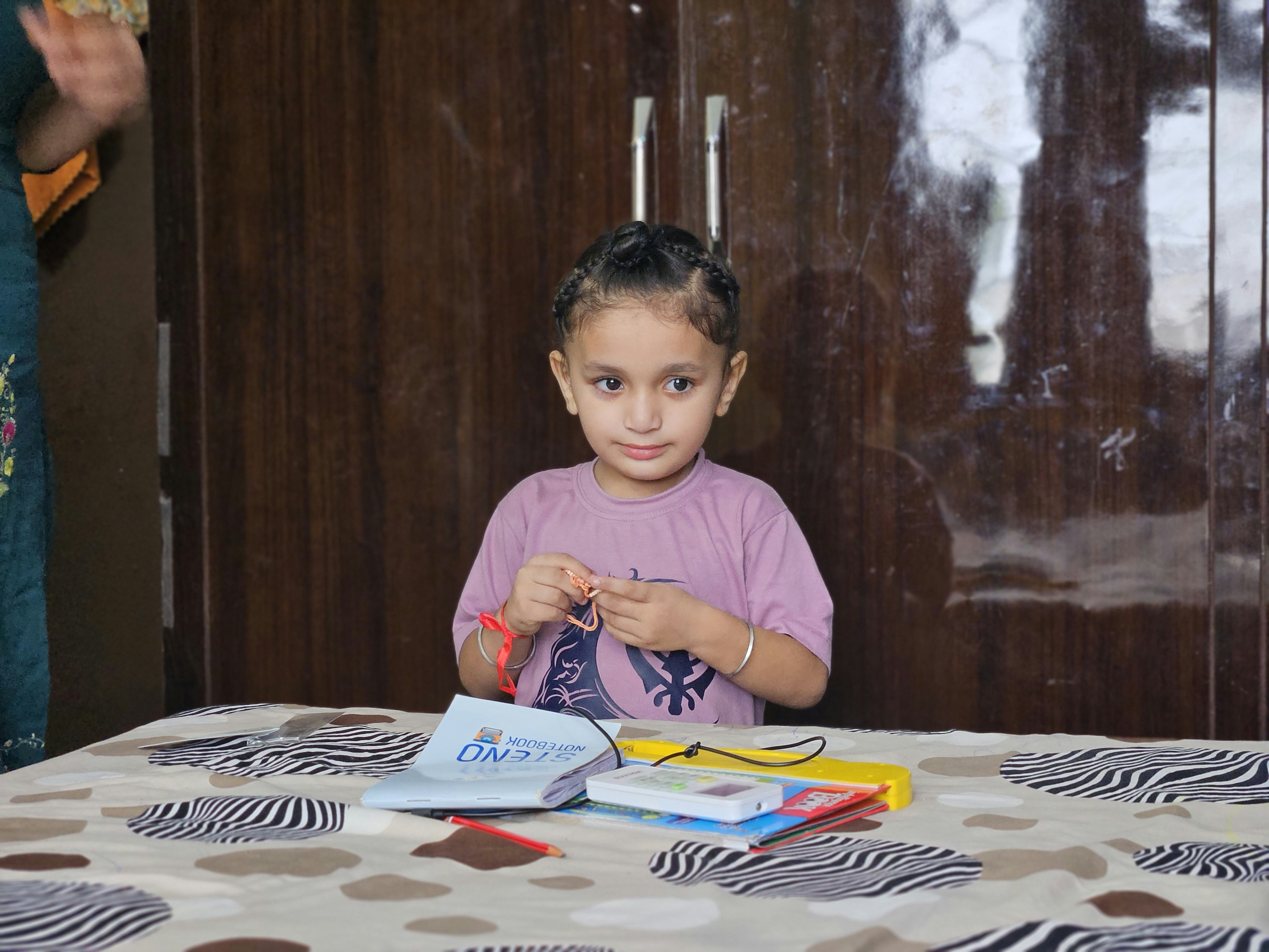 A young girl with braided hair sits at a table.