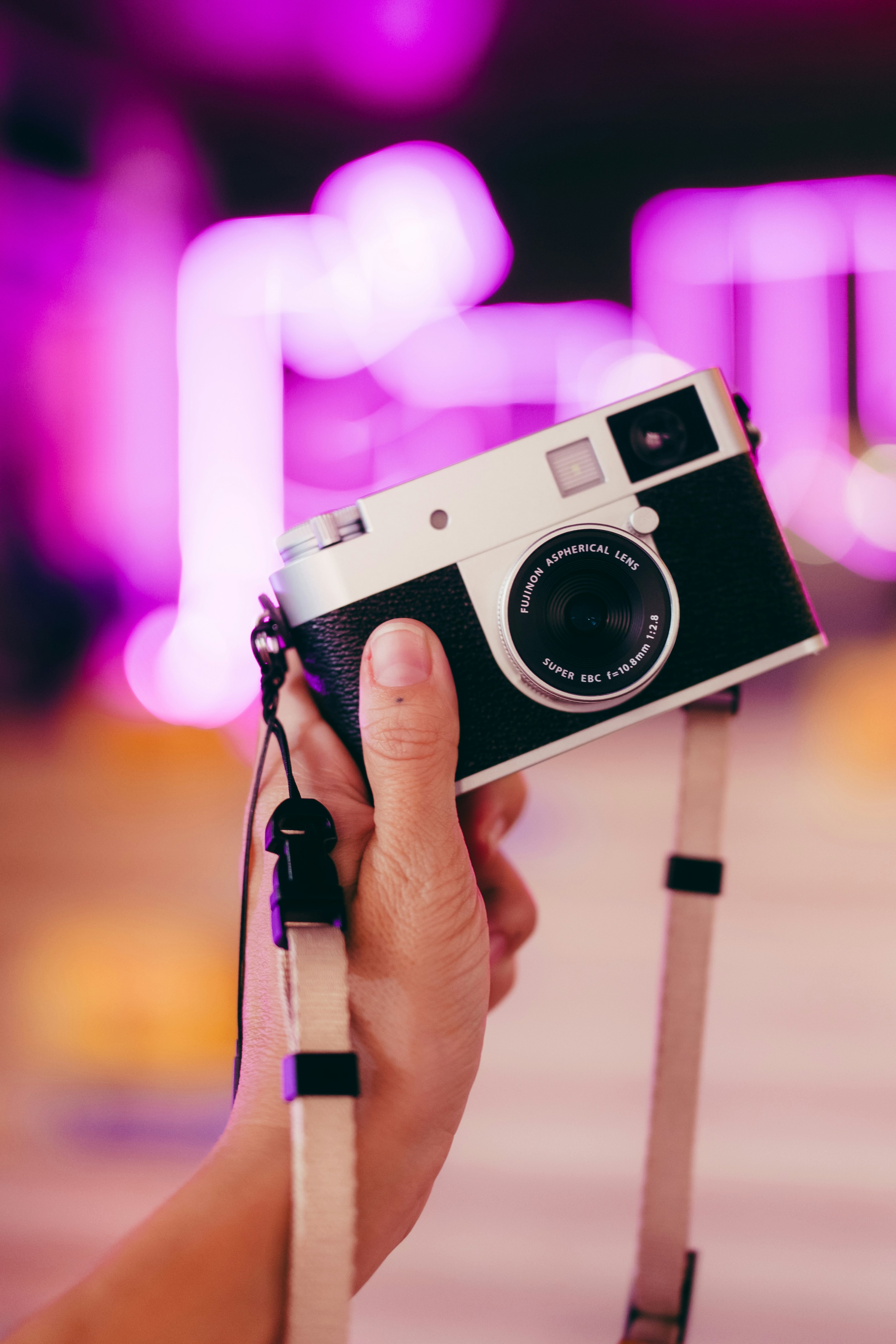 Hand holding a vintage camera with purple bokeh background
