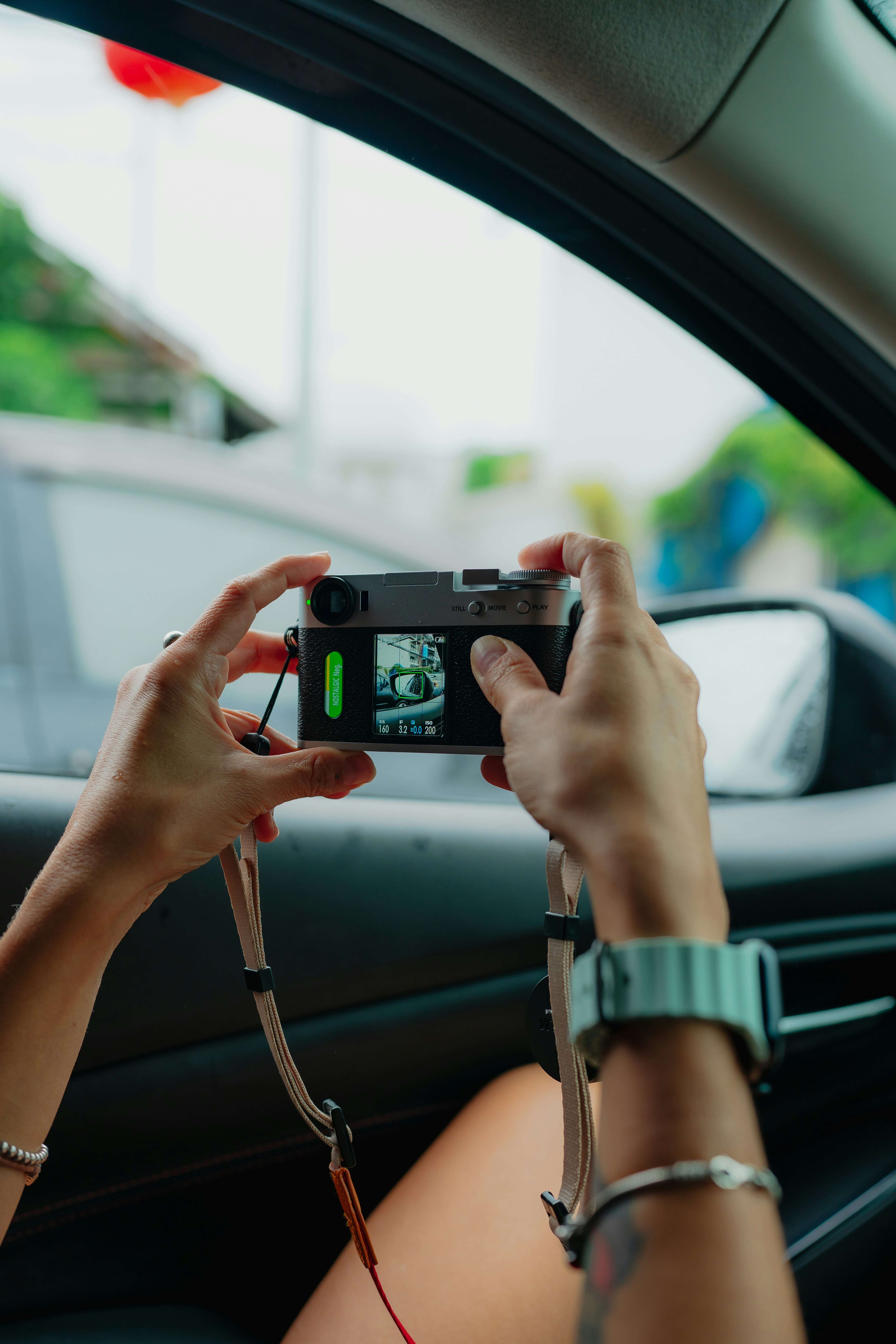 Hands holding vintage camera inside car