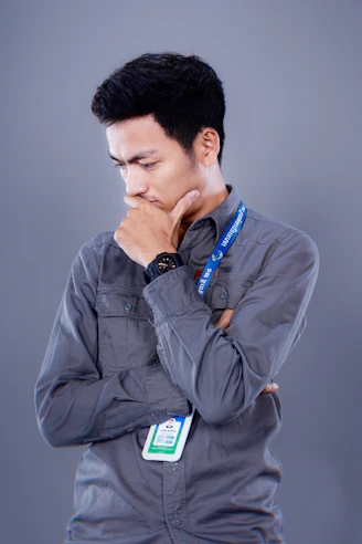 Man in gray shirt thinking with hand on chin