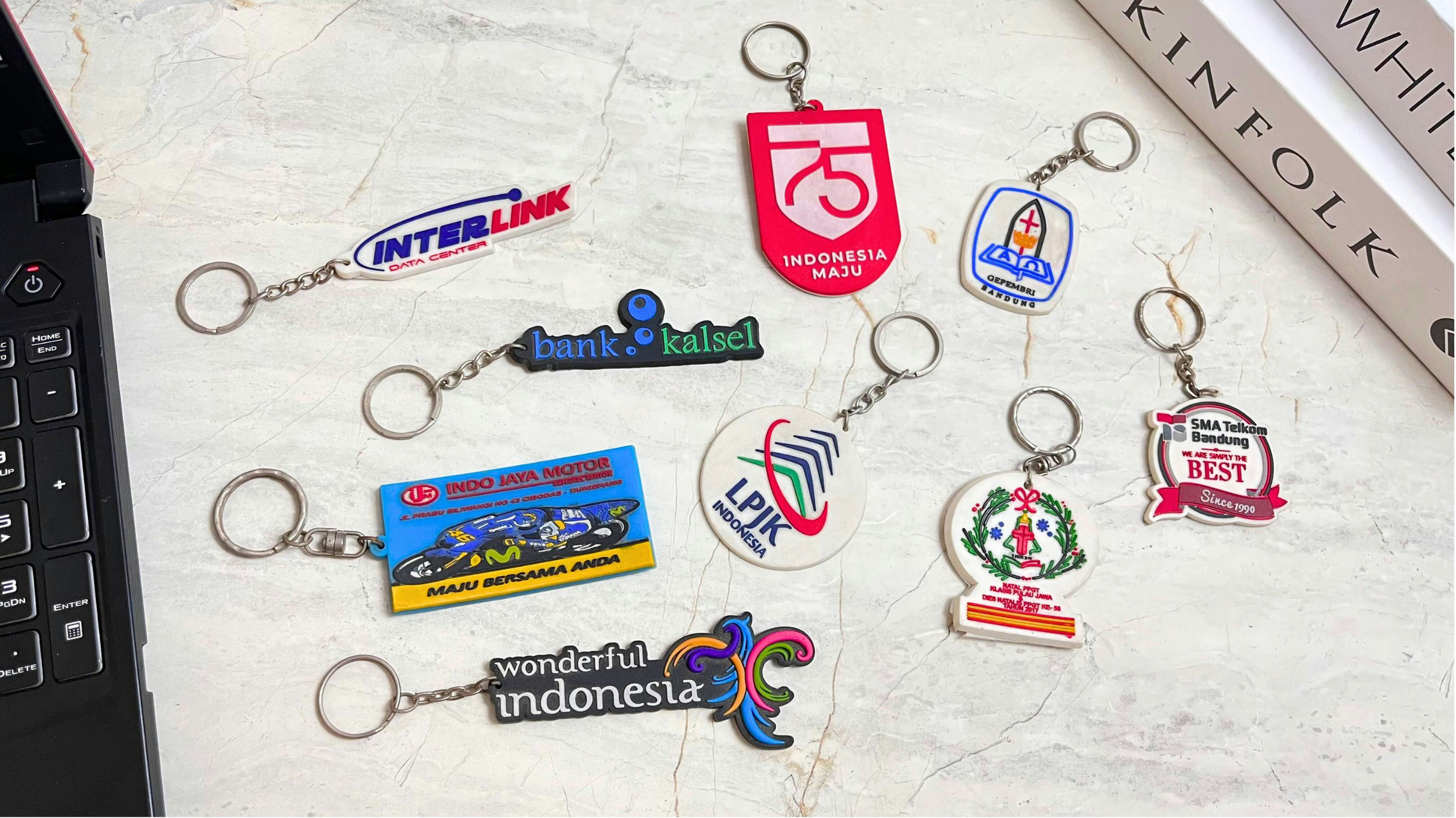 Custom keychains with various logos arranged on a marble surface.