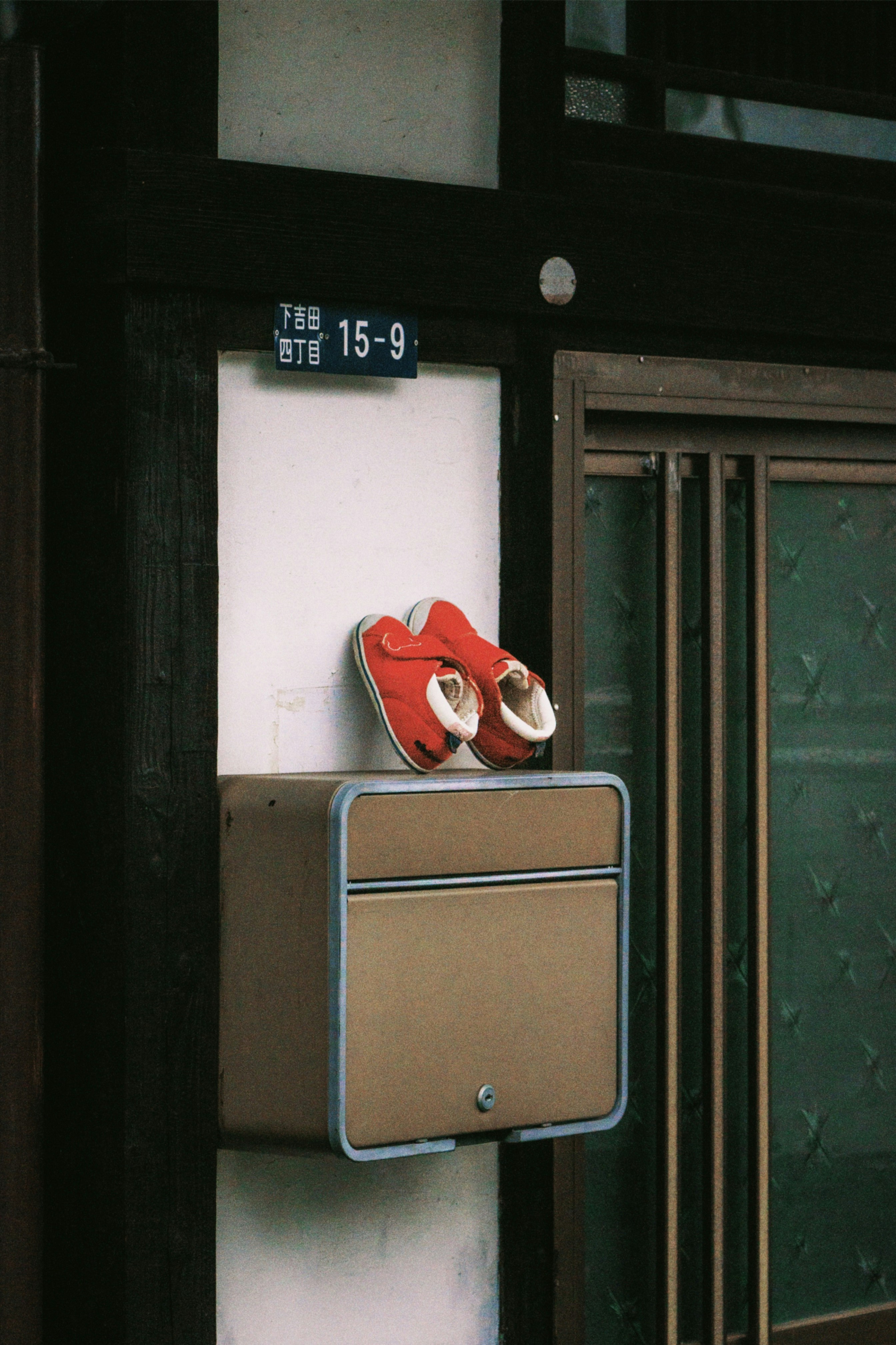 Red baby shoes resting on a mailbox