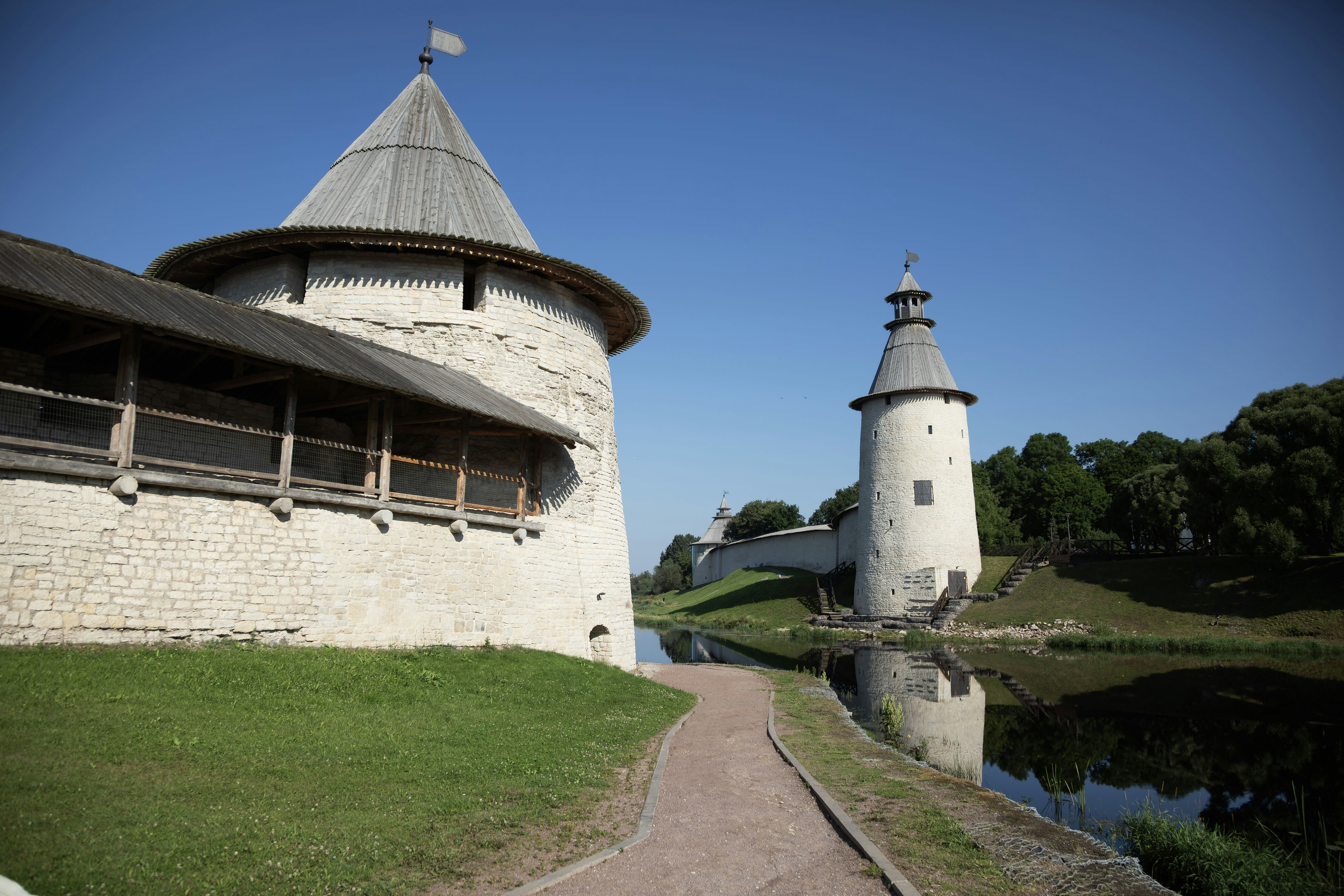 Stone fortress walls and towers by a calm river.