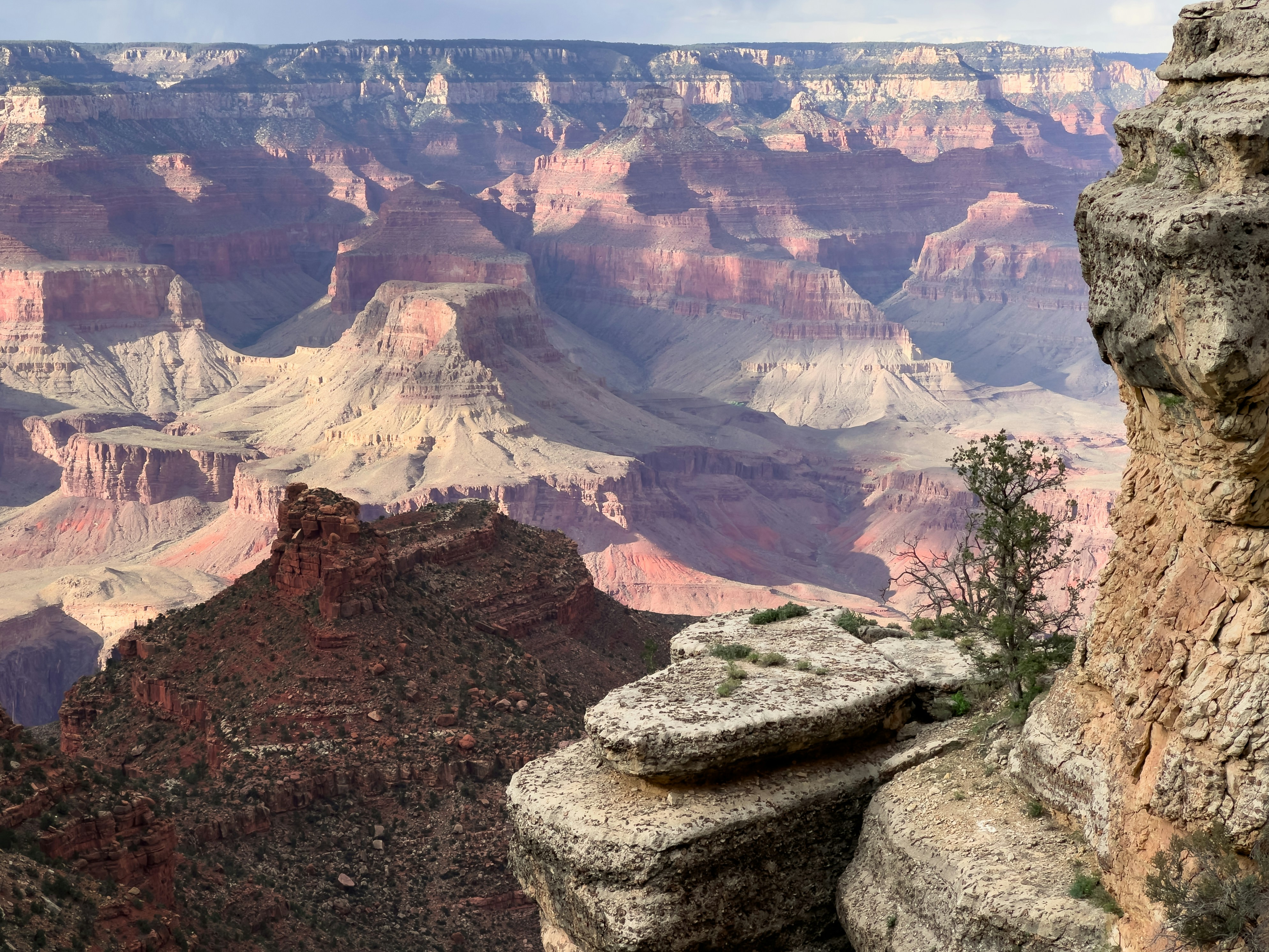 Grand canyon layered rock formations under a bright sky
