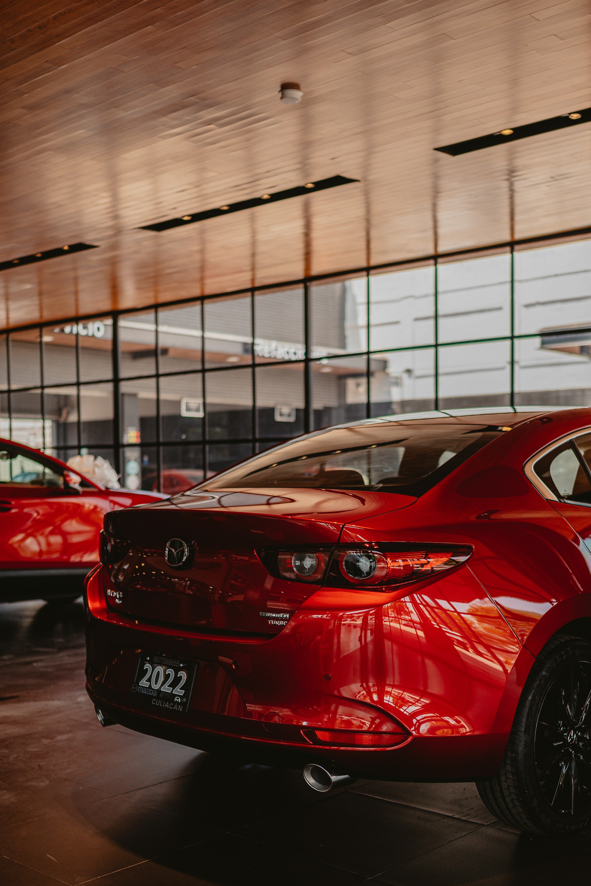 Red sedan parked indoors with a modern interior.