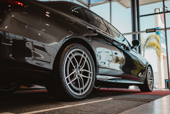 A sleek black car parked indoors with large windows