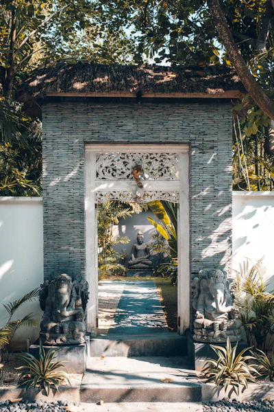 Ornate doorway with stone statues and lush garden beyond.