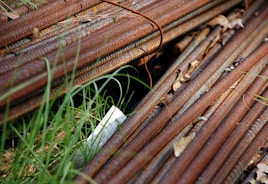 Stack of rusted metal rebar with grass and grass