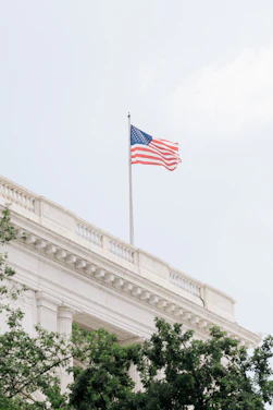 American flag waves atop a white building.