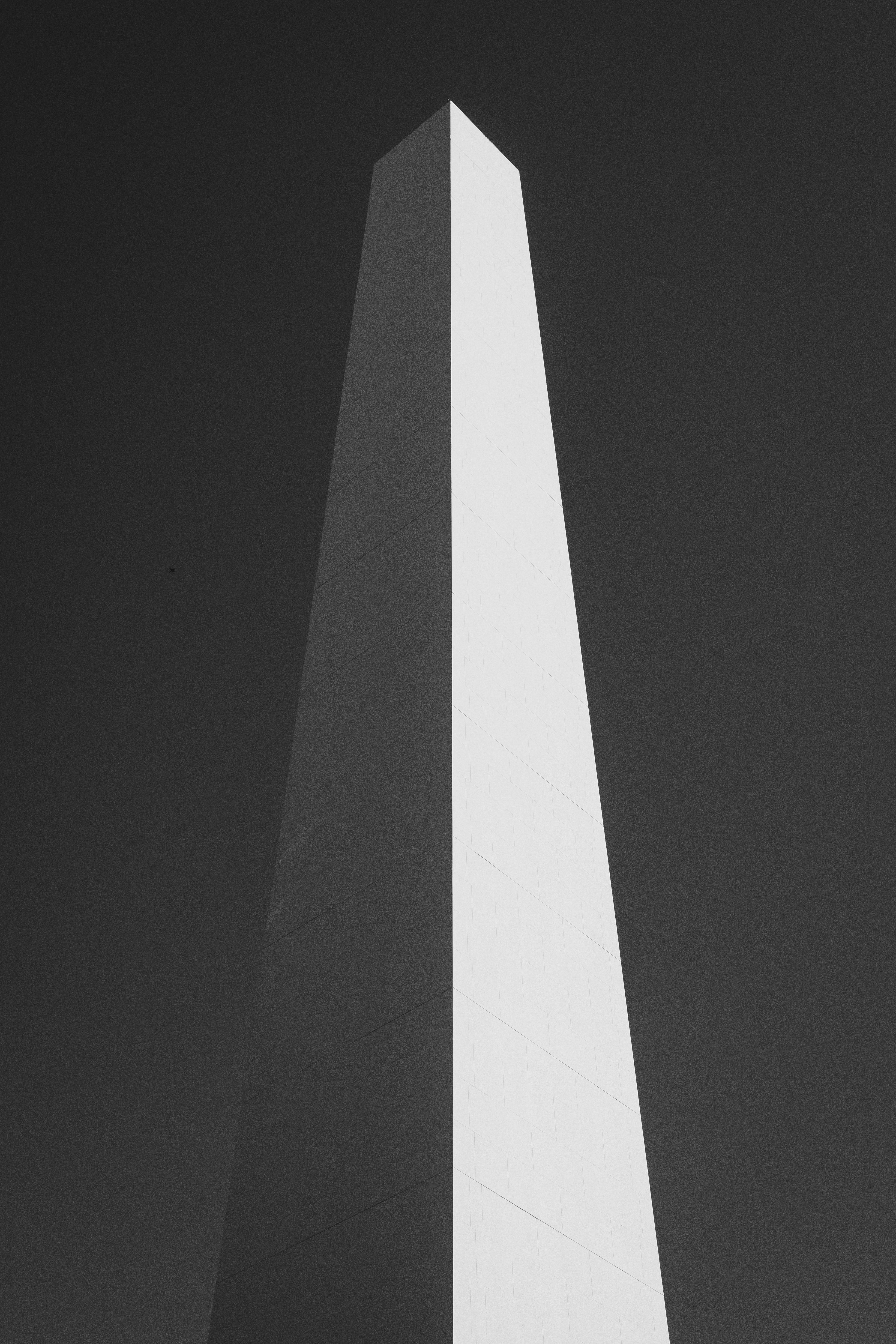 Tall white obelisk against a dark sky