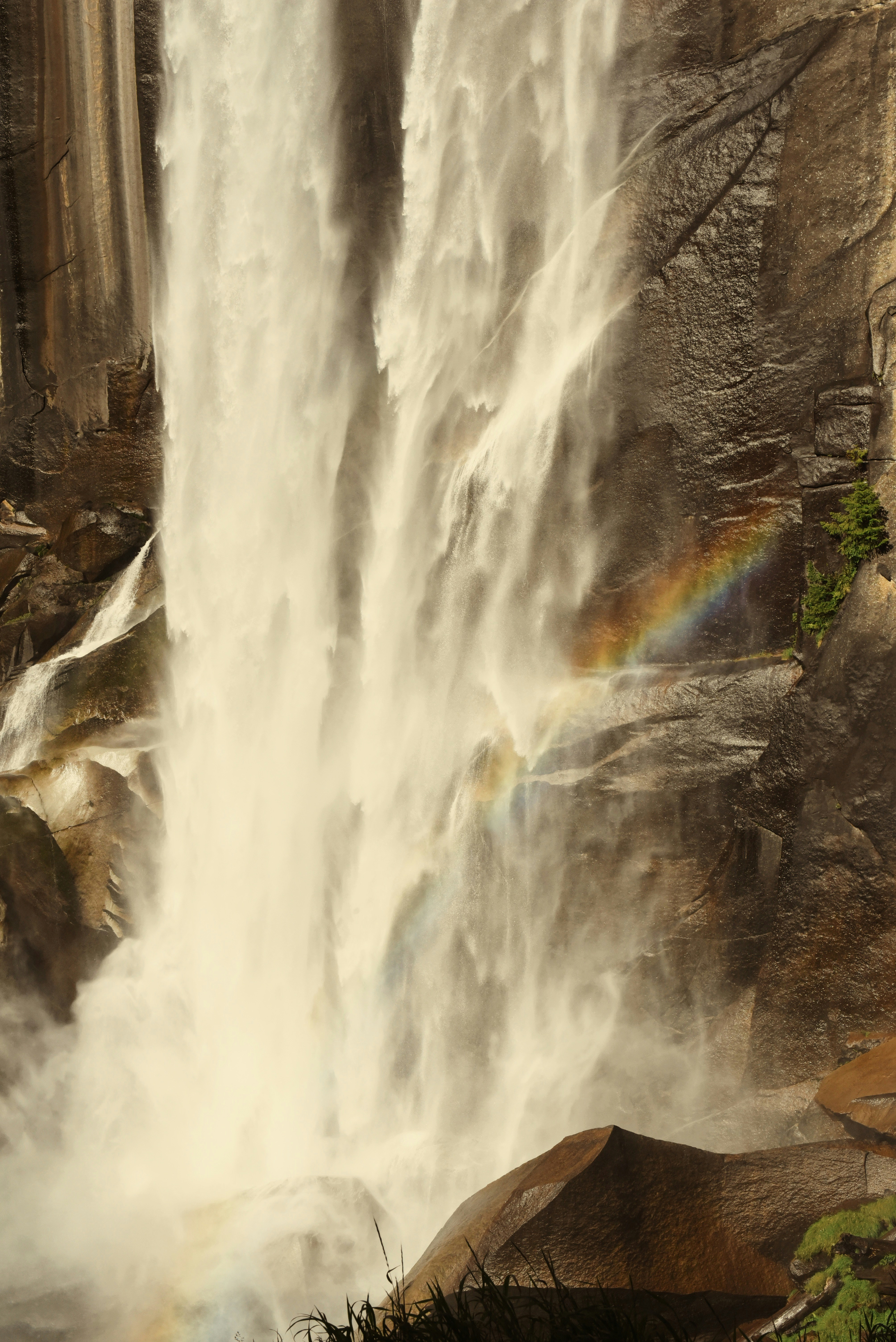 Waterfall cascading down a rocky cliff with a rainbow