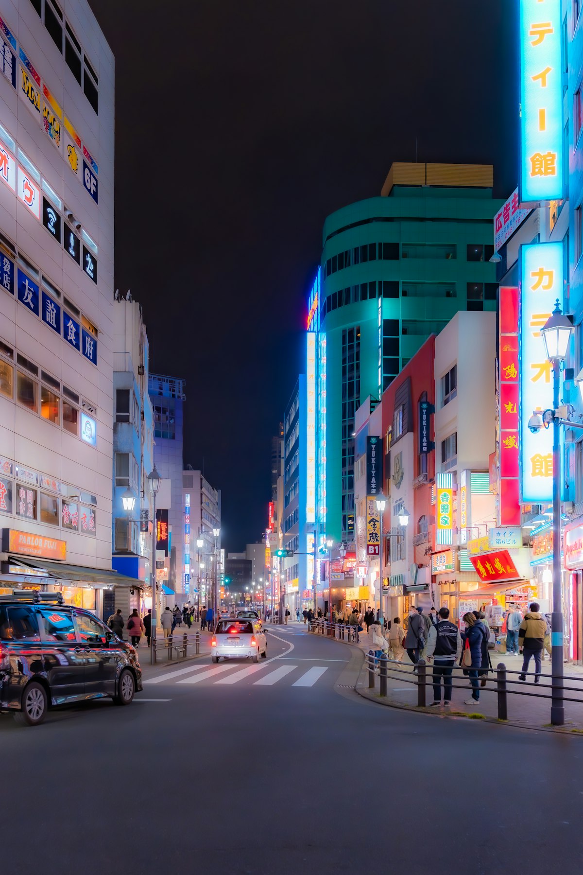 A busy Tokyo street at night, drenched in neon signs and reflections