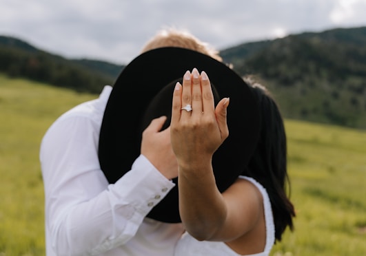 Couple showing engagement ring with hat