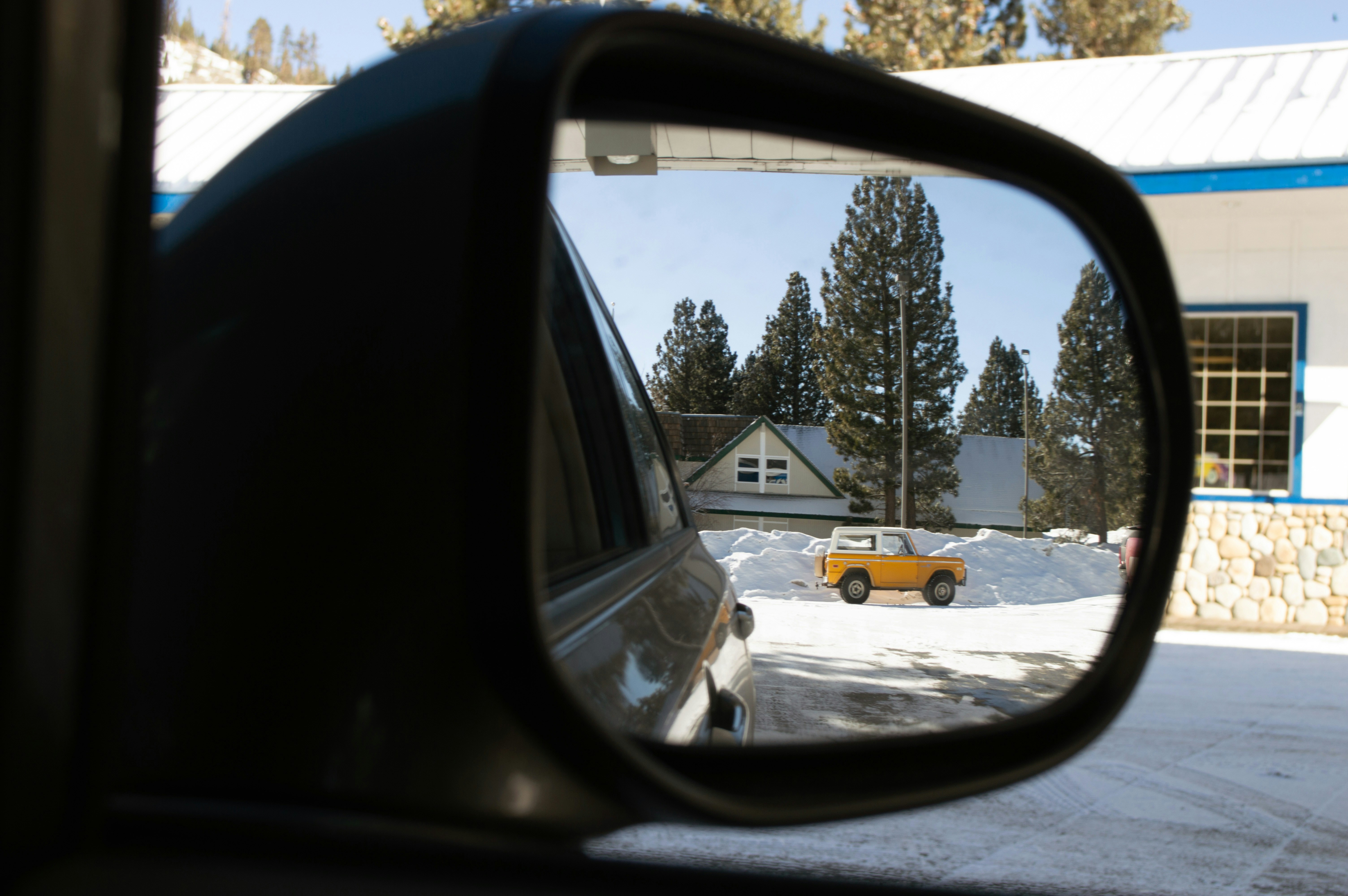 Yellow car reflected in side mirror with snowy background
