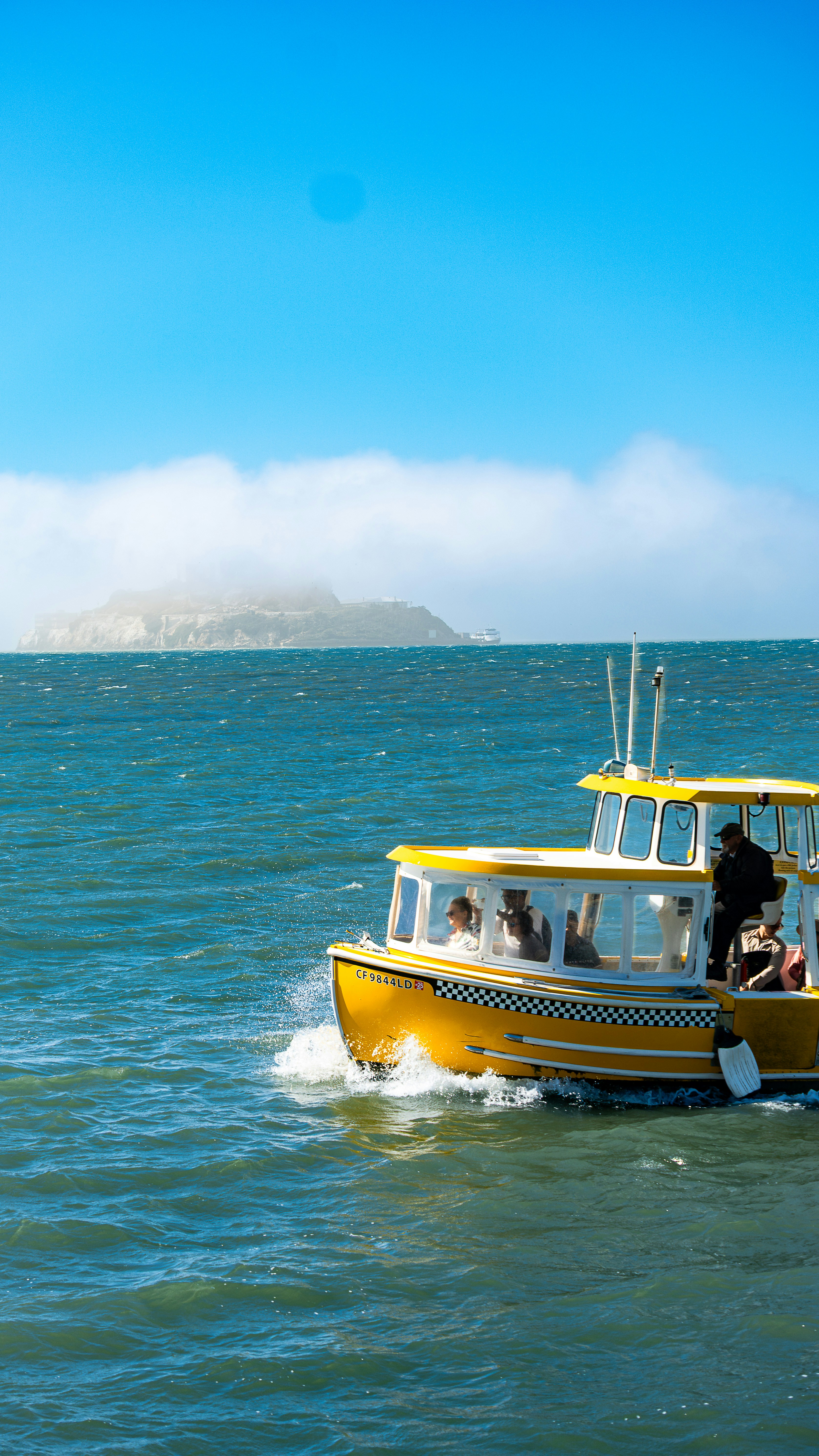 Yellow ferry boat sailing on choppy blue water