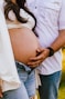 Couple holding pregnant belly outdoors