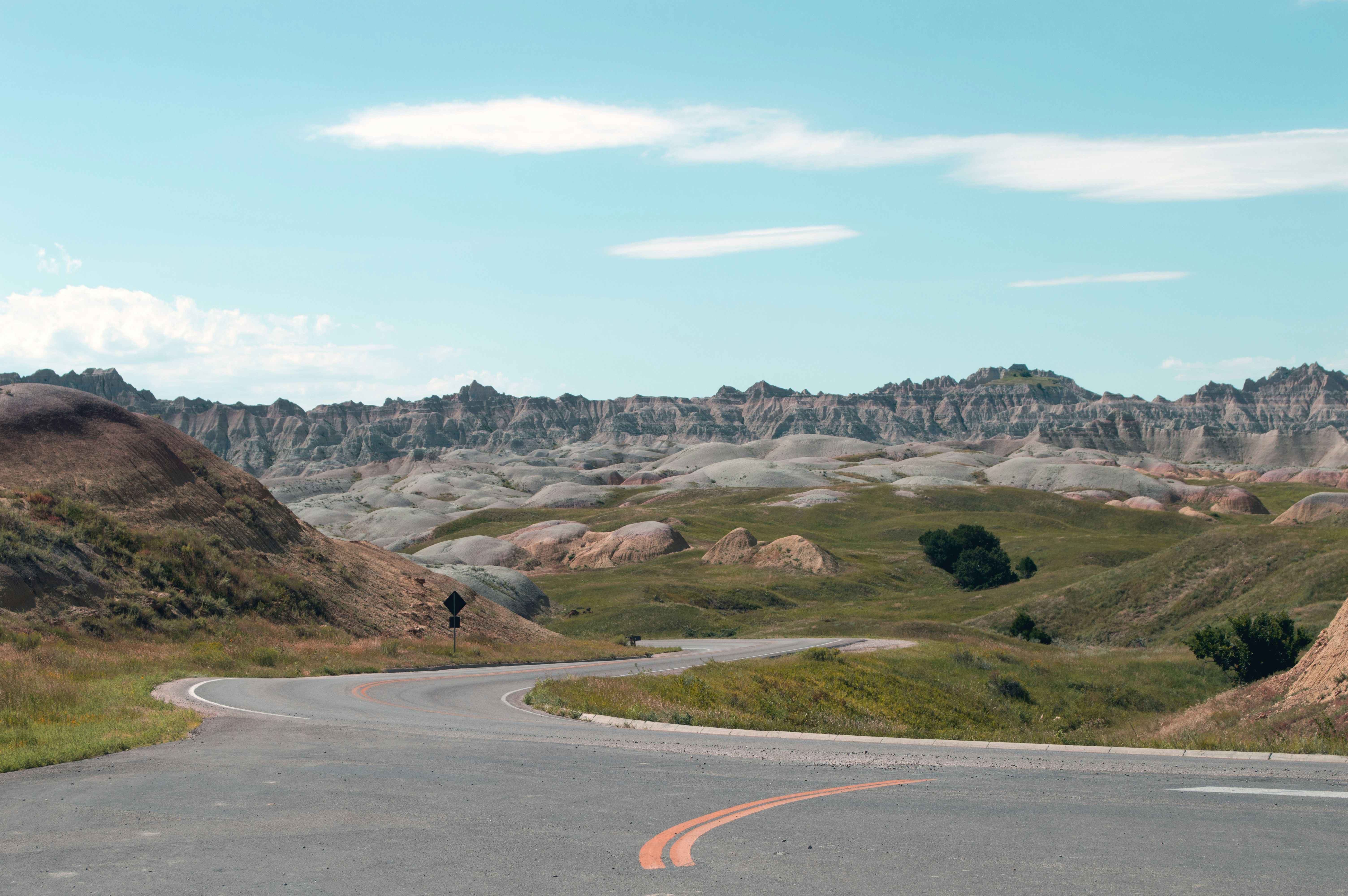 Winding road through rugged badlands under a blue sky.