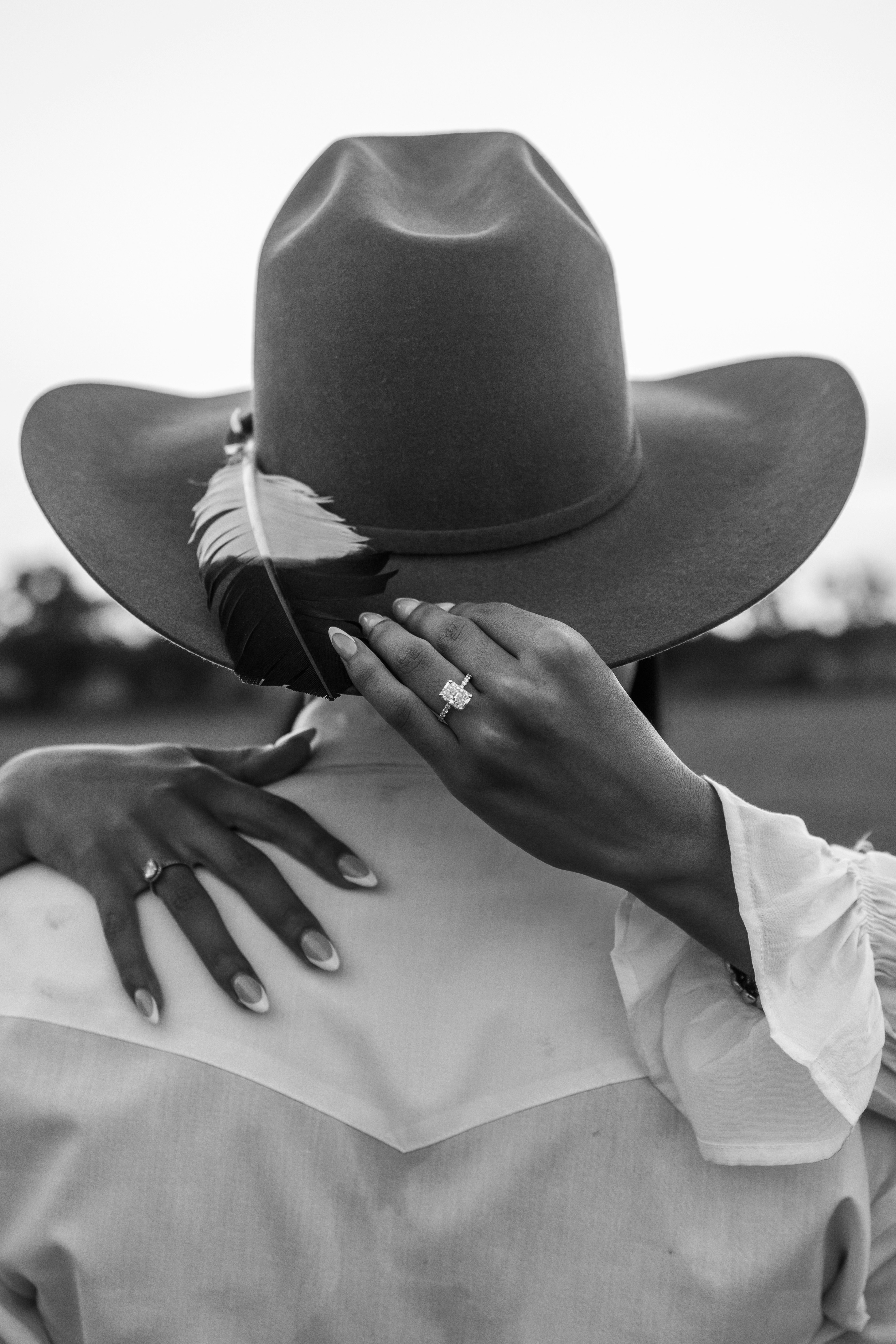 Couple embracing wearing cowboy hats and rings