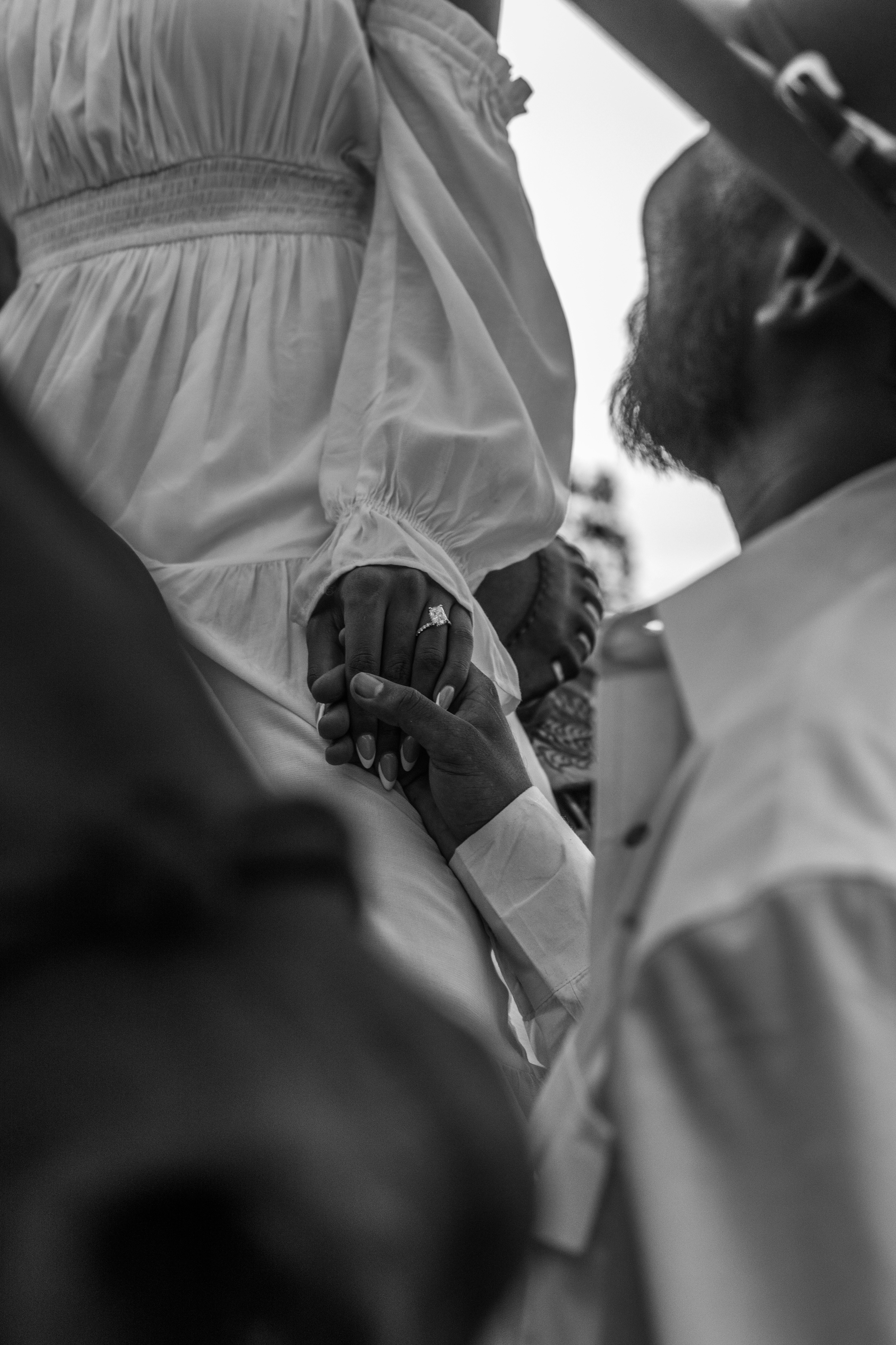 Couple holding hands with engagement ring visible