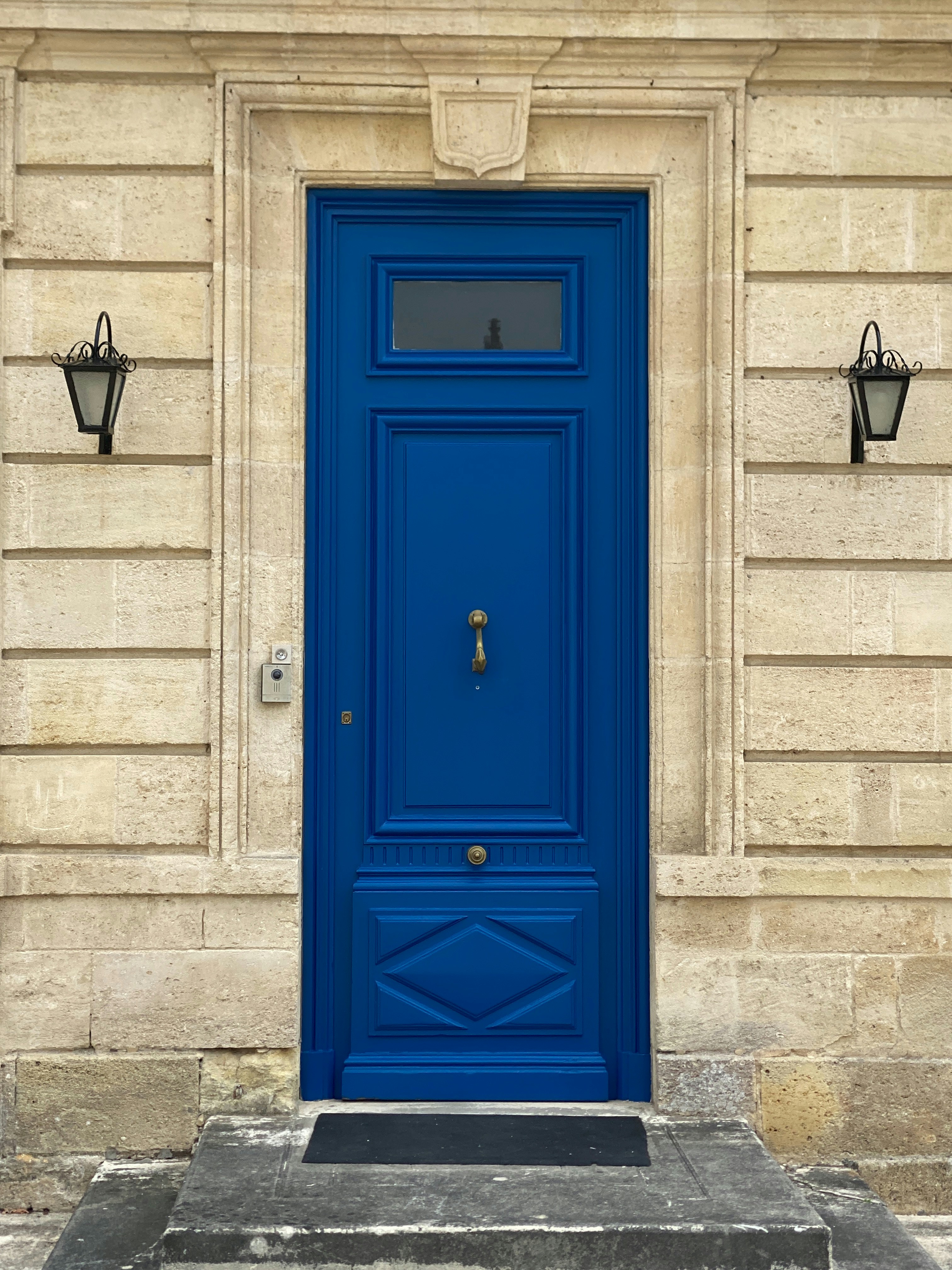 A bright blue door with ornate panels and lanterns.