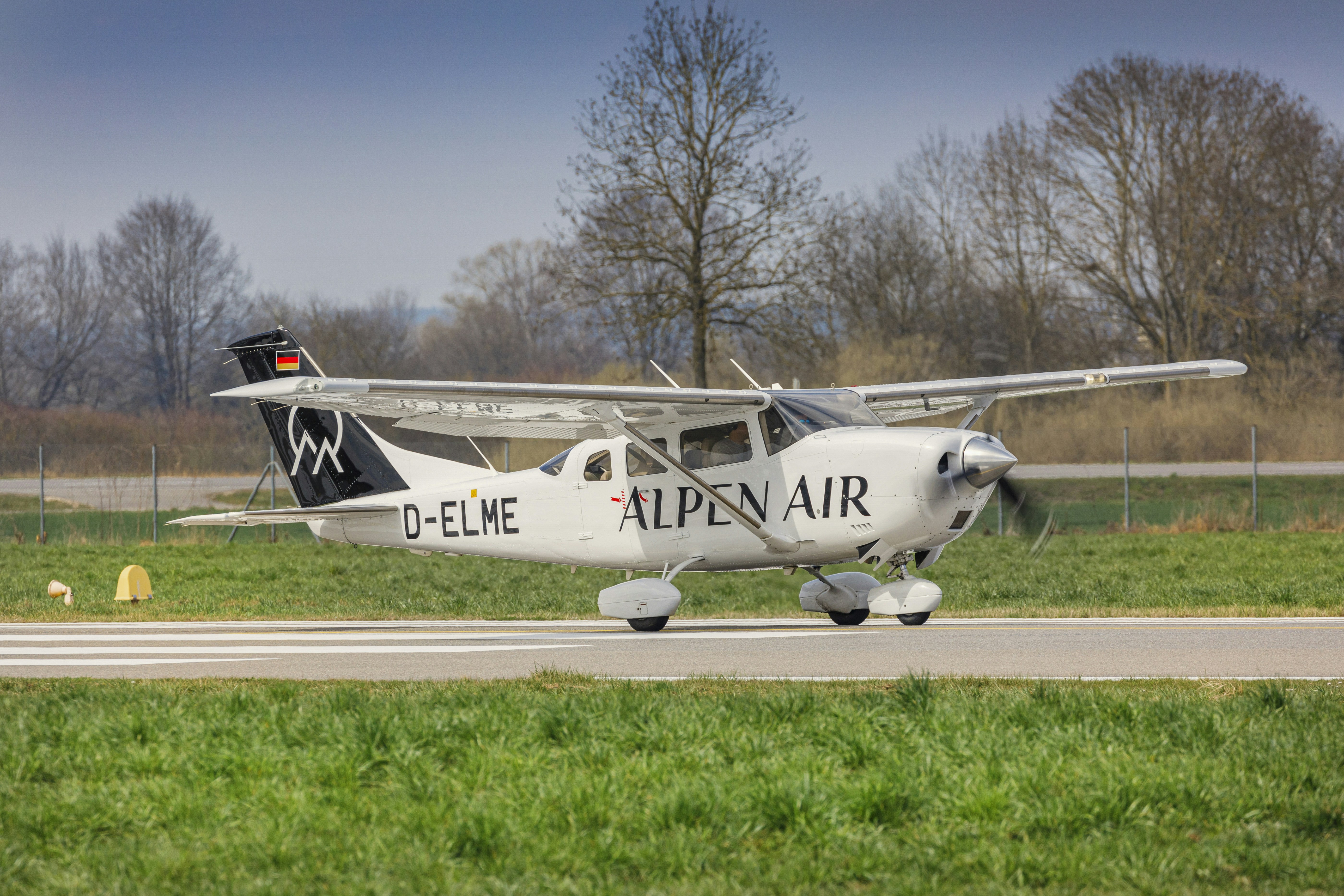 Small white airplane on a runway with trees