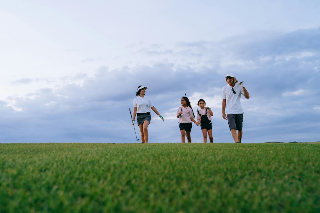 Family with golf clubs walking together on a sunlit course
