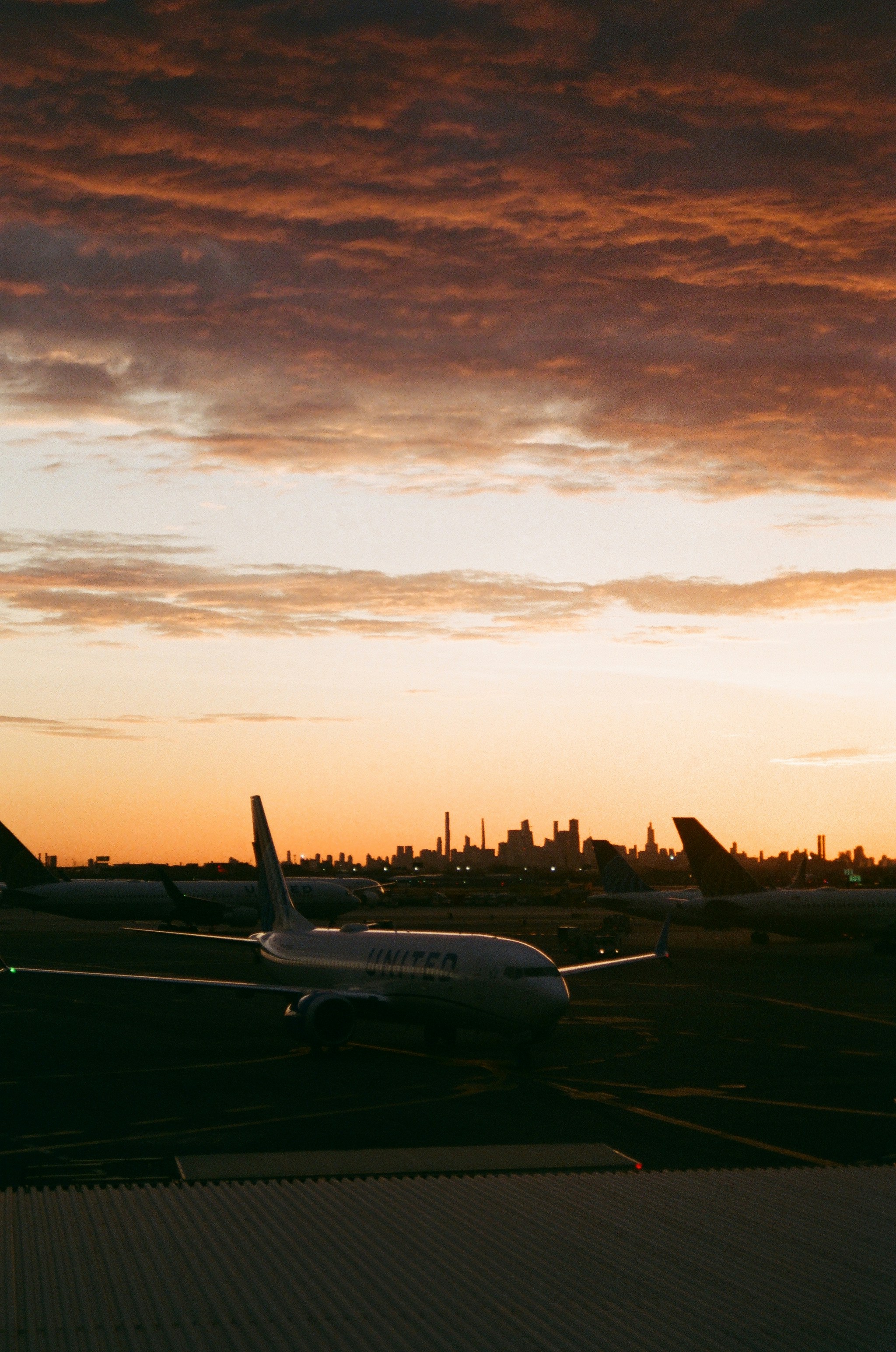Airplane on tarmac with city skyline at sunset