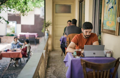 Man working on laptop at outdoor cafe table