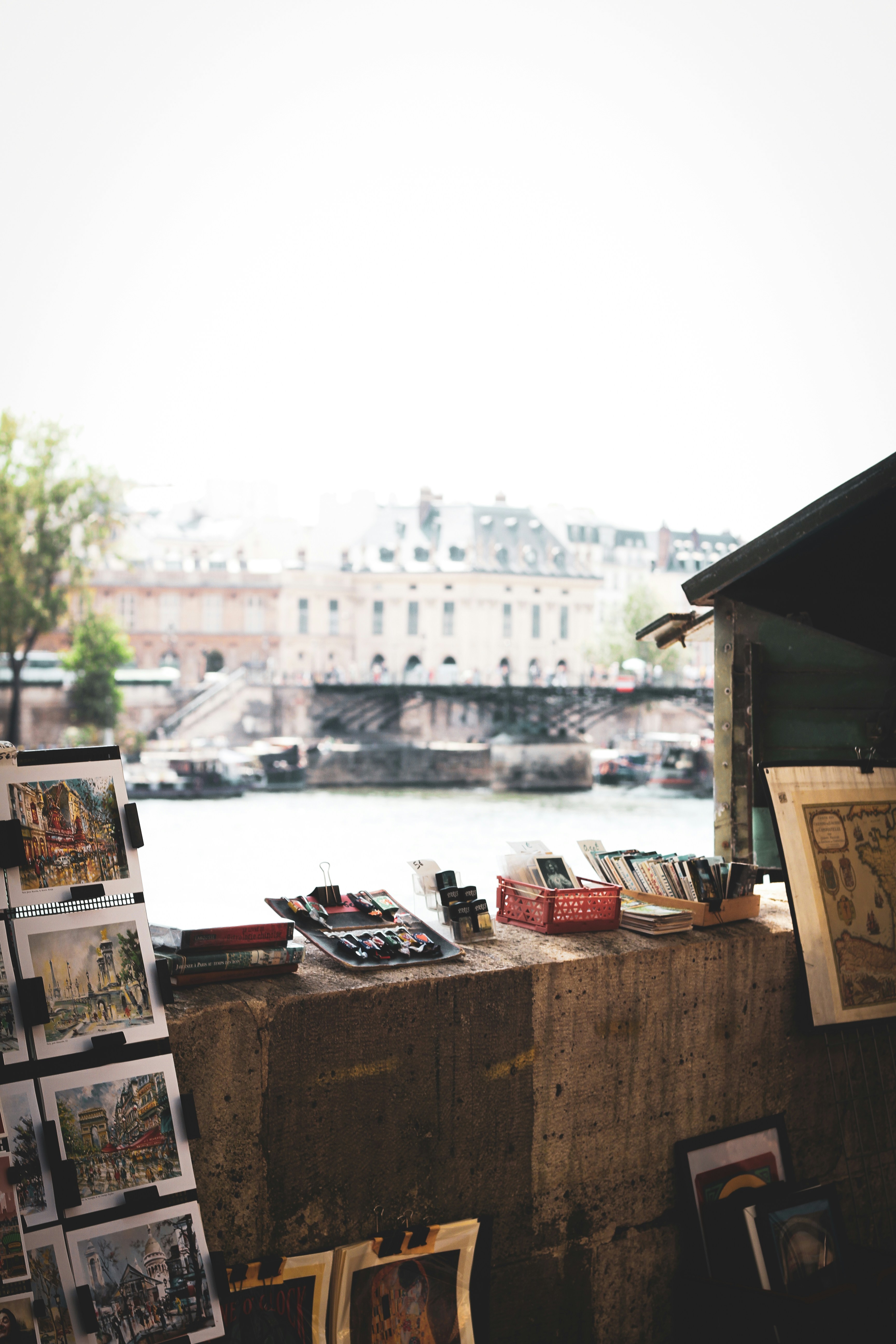 Postcards and art displayed by a river with buildings.