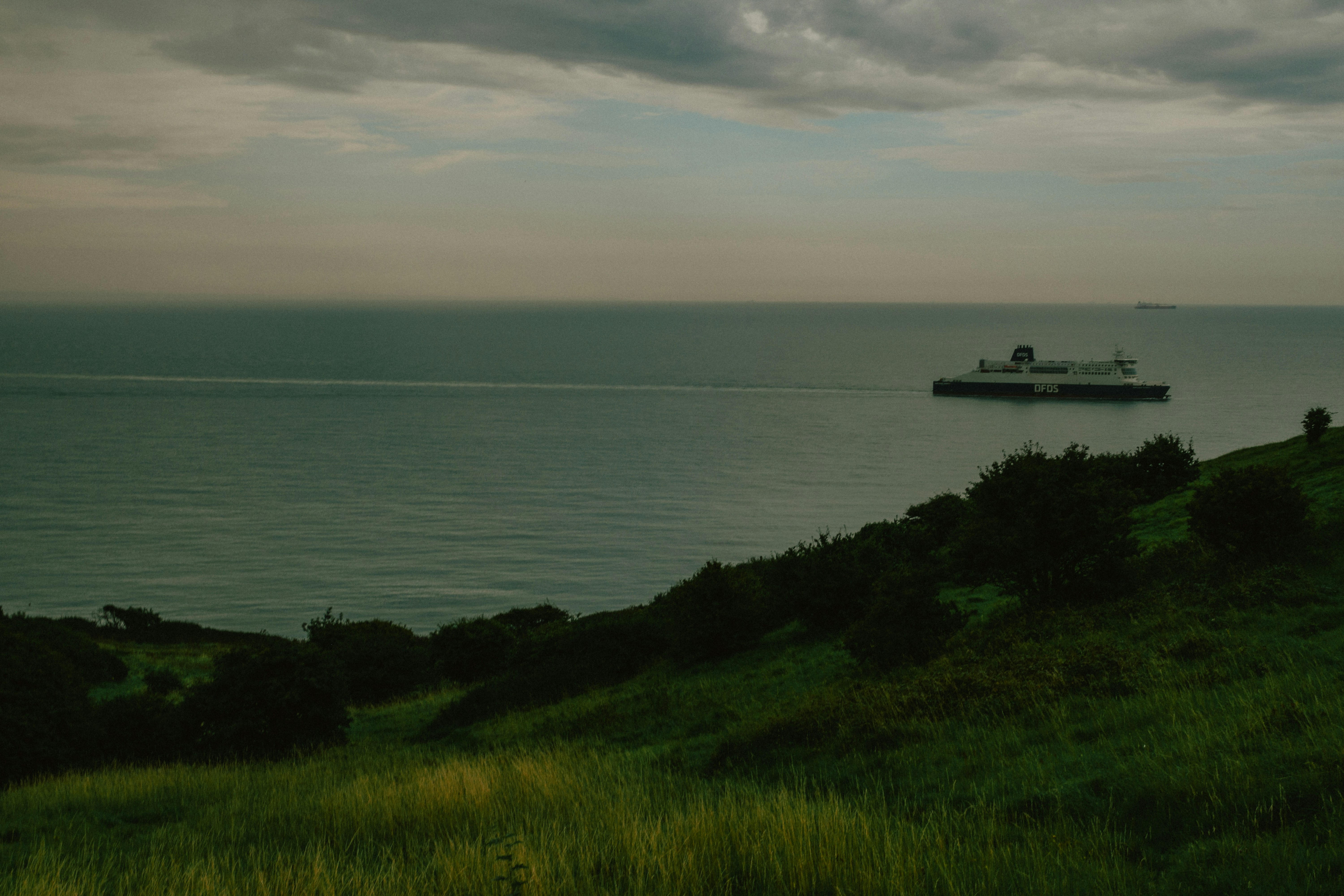 Eine Fähre segelt auf ruhiger See in Küstennähe.