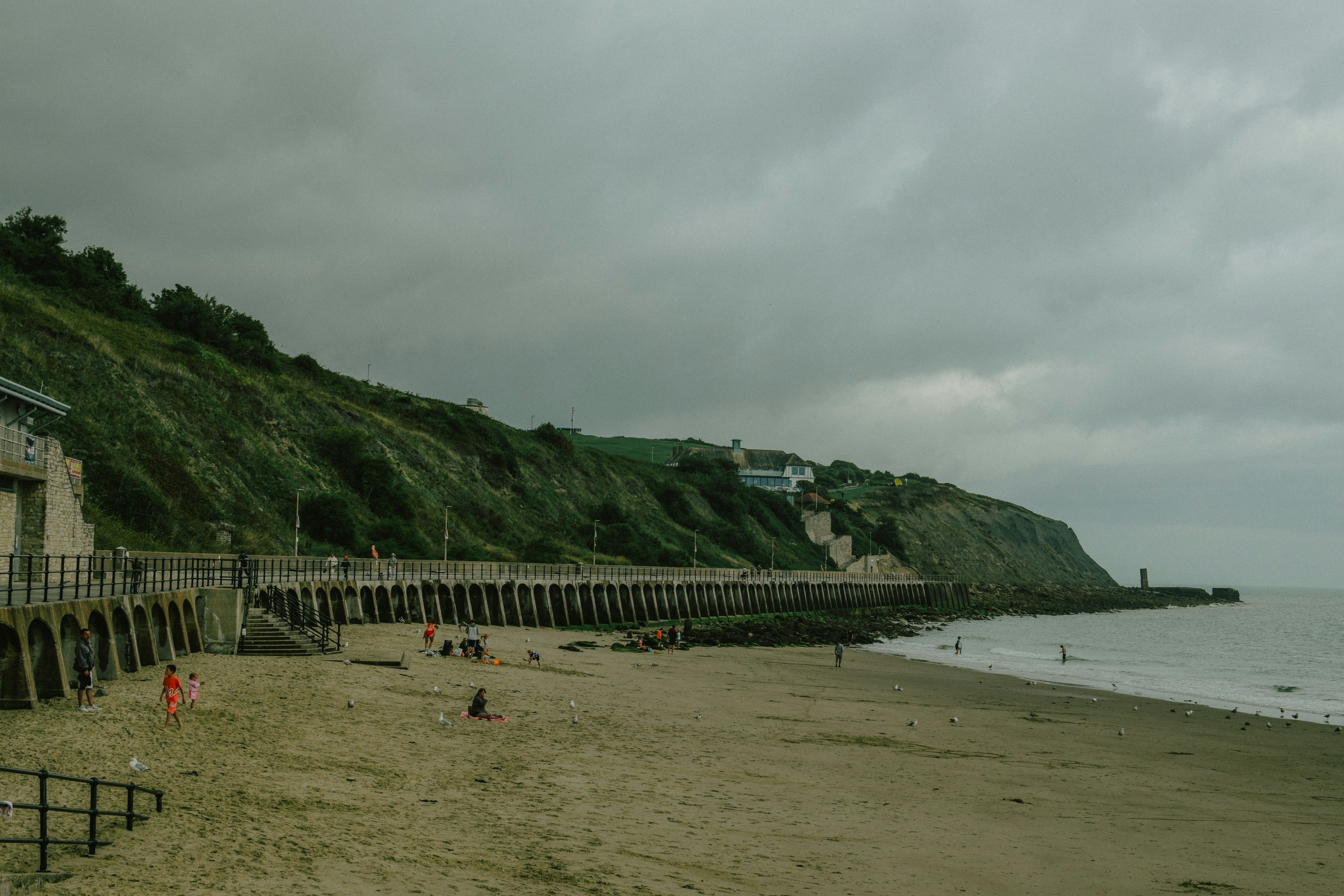 Sandstrand mit Promenade und grasbewachsener Steilküste