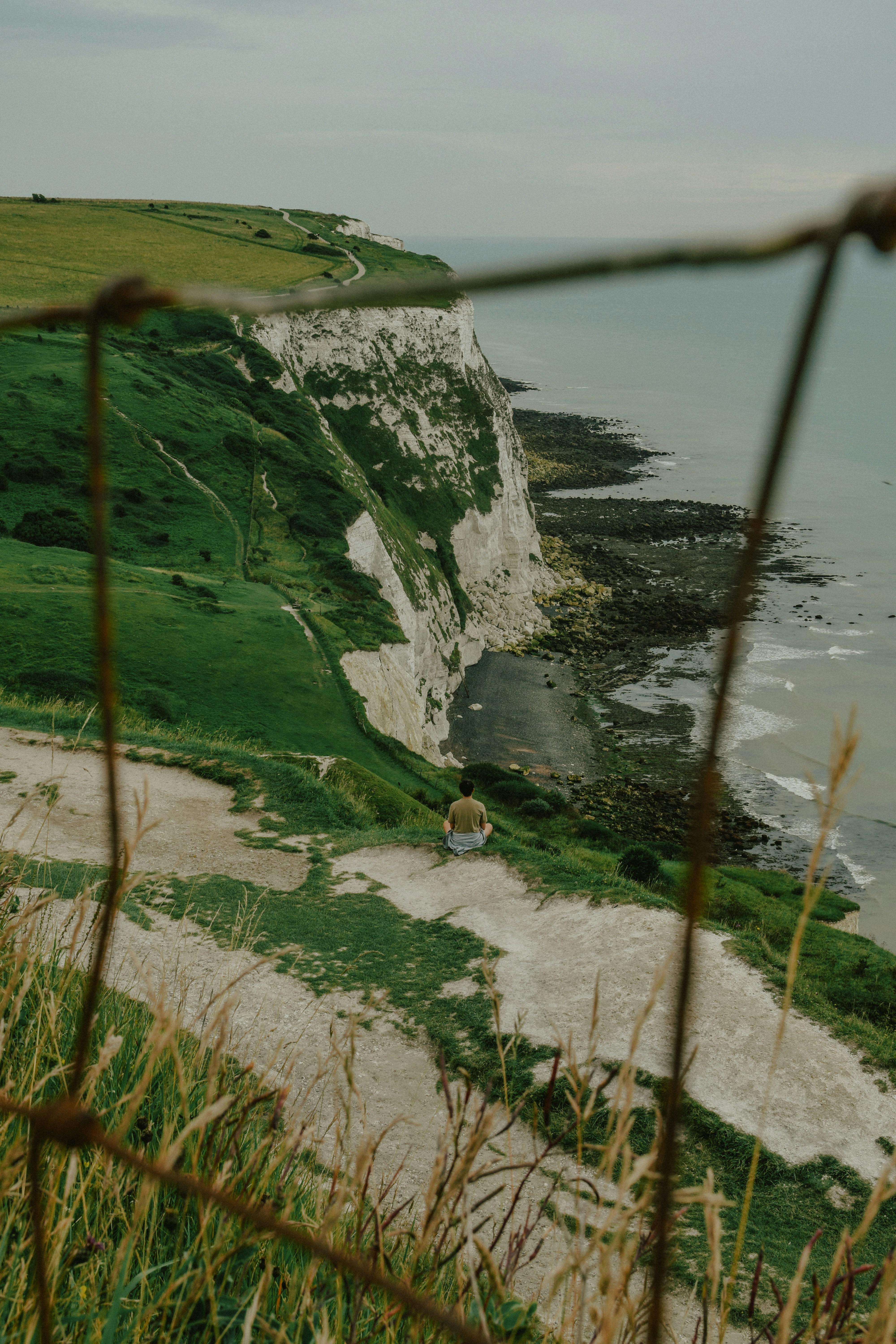 Person, die auf einer Klippe sitzt und den Ozean überblickt