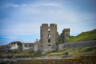 Stone castle ruins on a grassy hill under sky