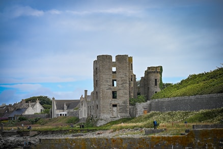 Stone castle ruins on a grassy hill under sky