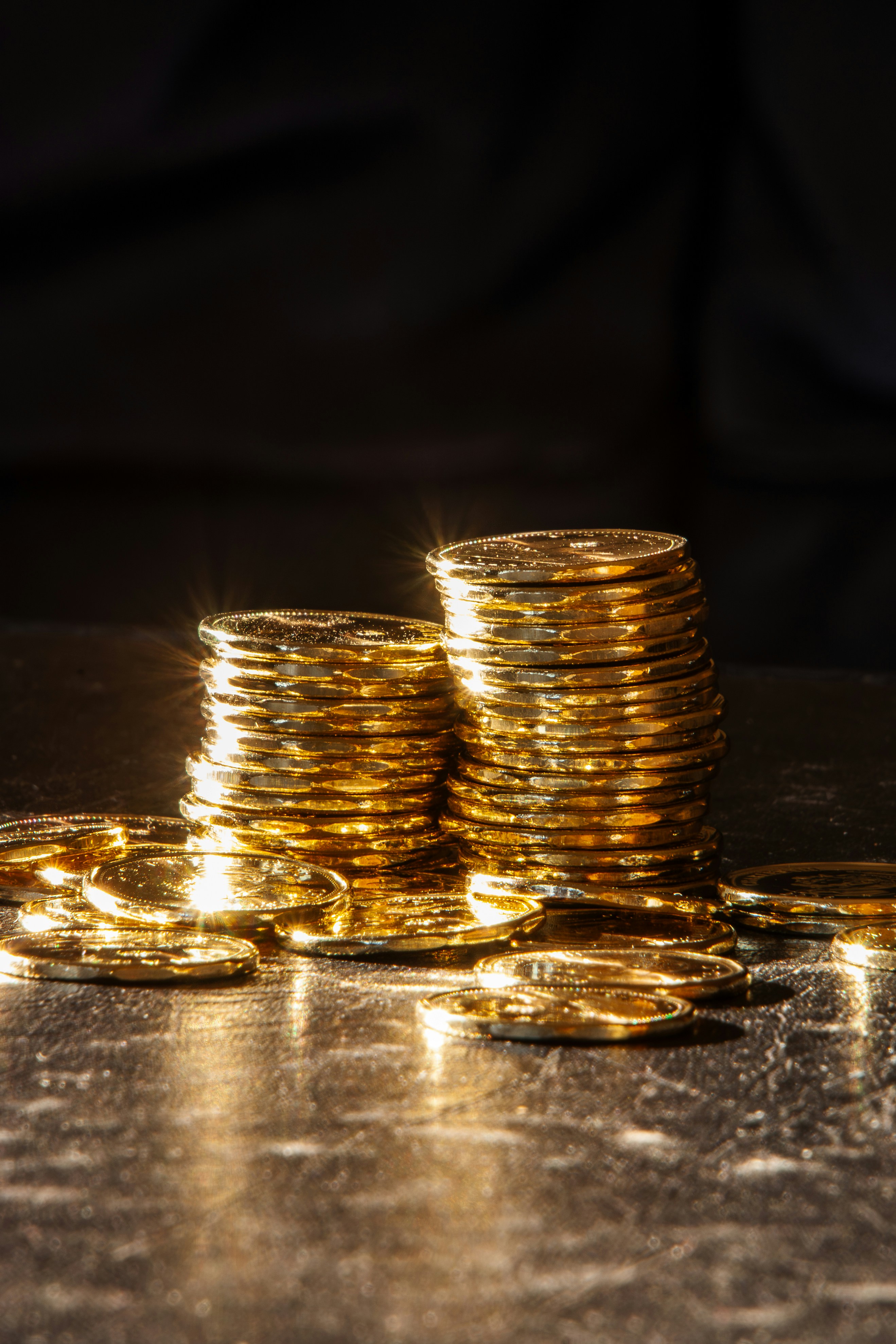 Two stacks of gold coins on a dark surface