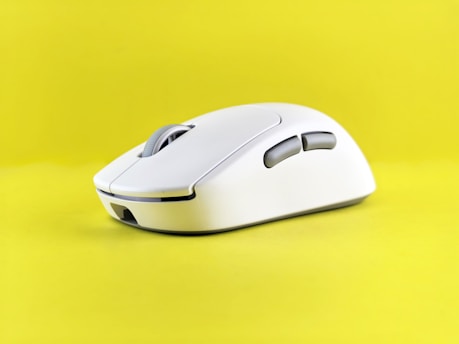 A white computer mouse on a yellow background